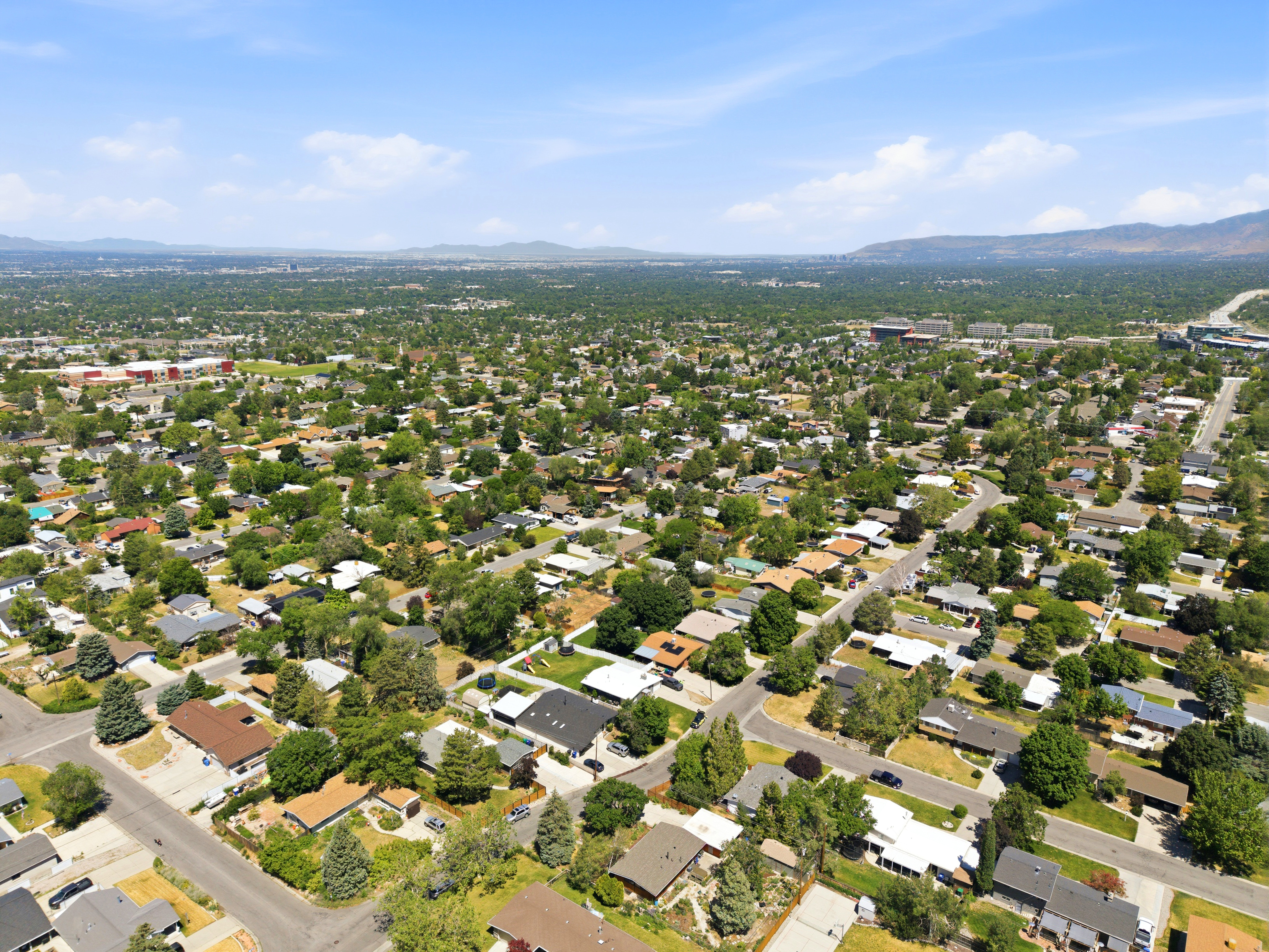 Expansive residential area featuring numerous single-family homes, mature tree coverage, and mountain backdrops