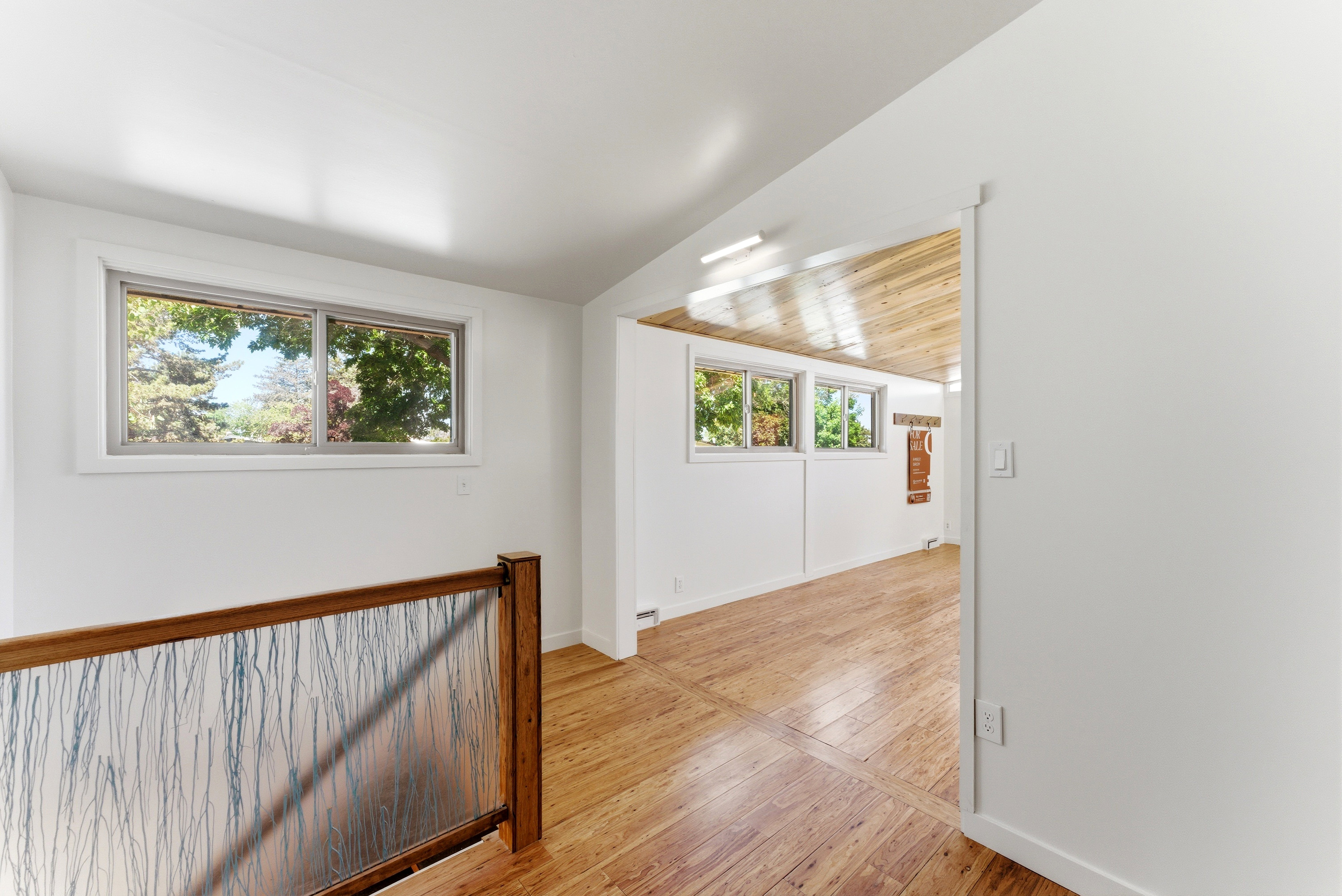 Bright interior space featuring wood-finish flooring, white walls, and a wood-paneled ceiling