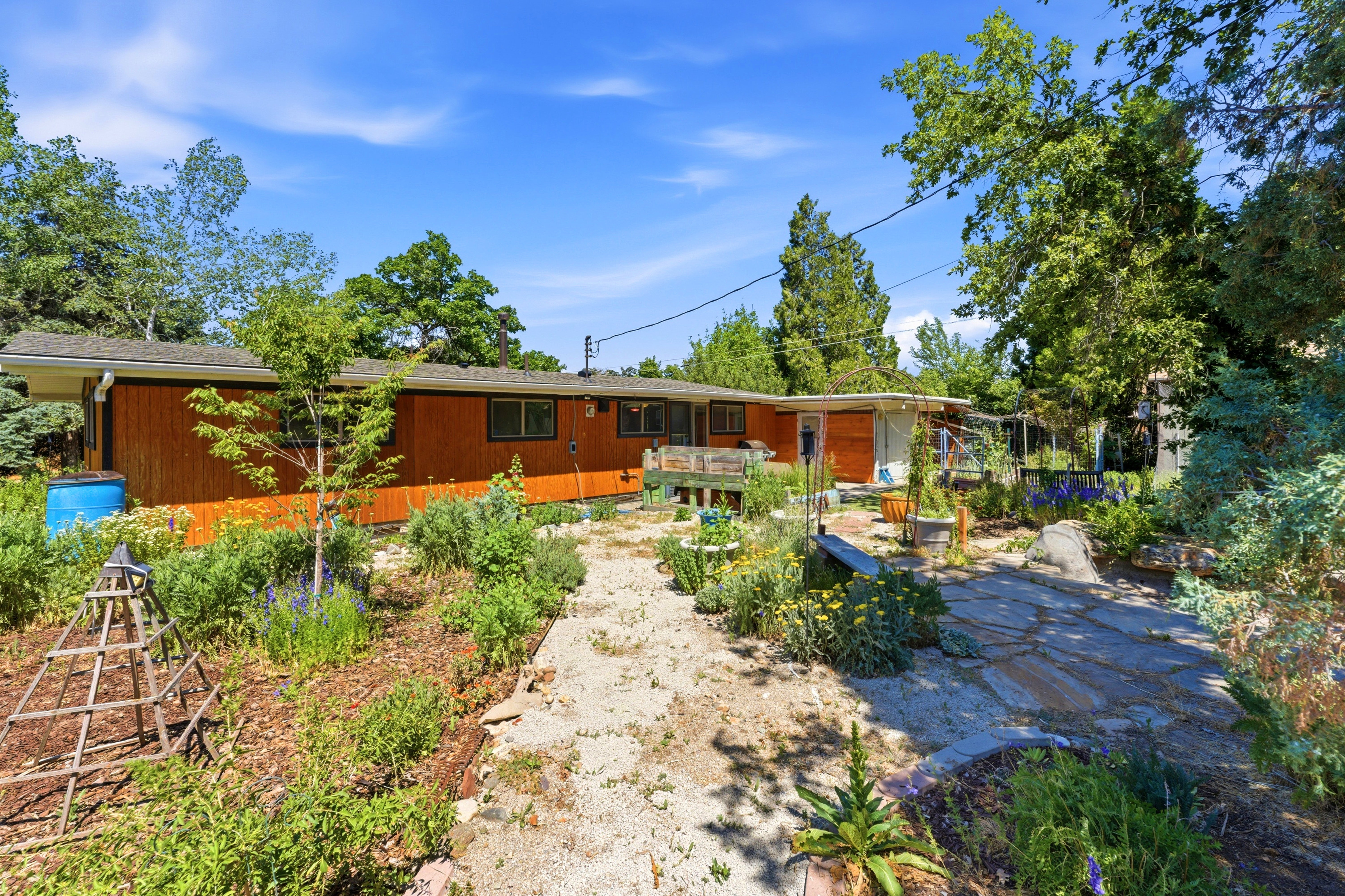 The property features wood siding and a private garden area with a path leading towards the residence