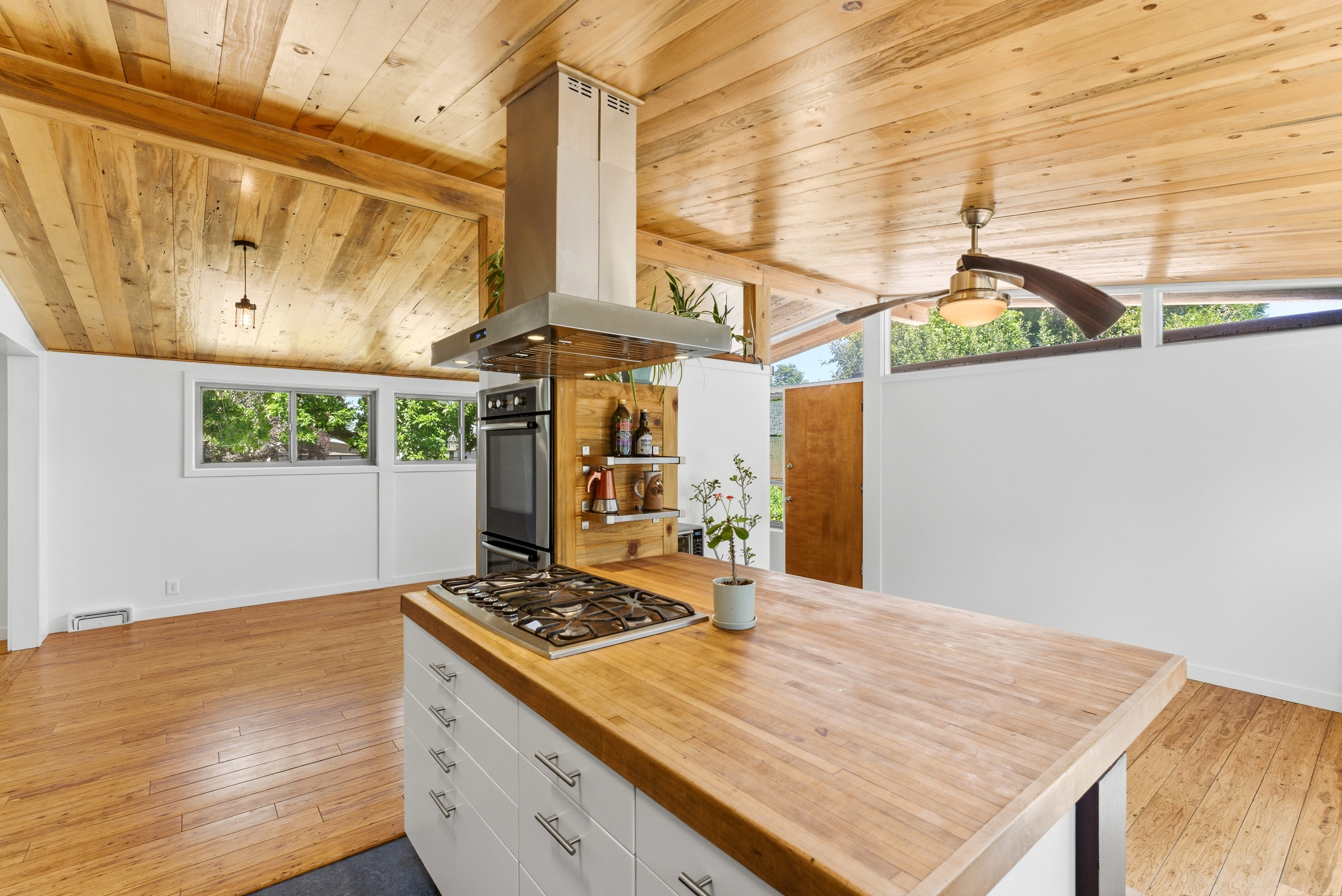 Kitchen island with a built-in gas cooktop, wood-finish countertop, and white cabinetry