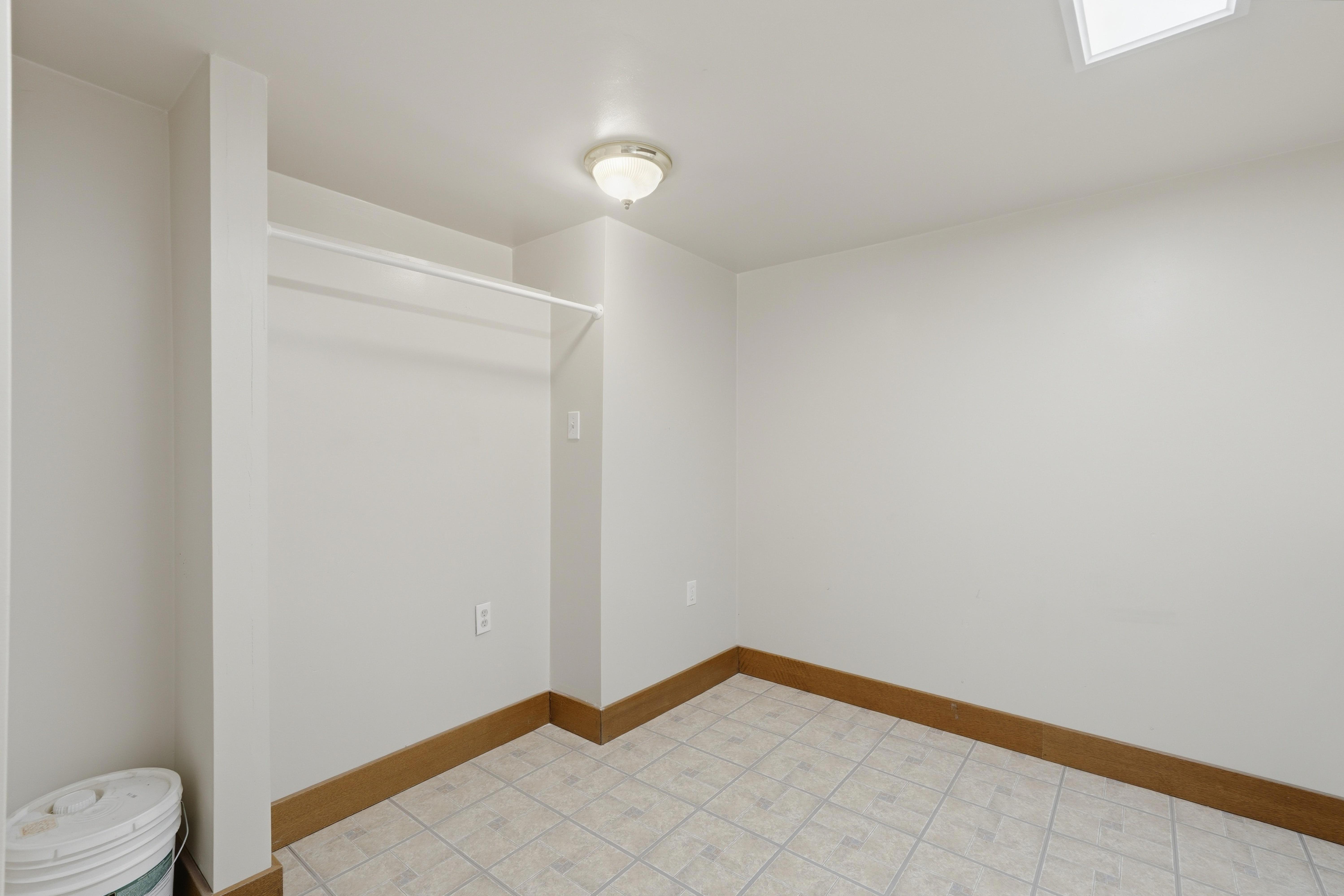Room featuring light-toned walls, a built-in clothing rod, wood-finish baseboards, and a semi-flush mount ceiling light