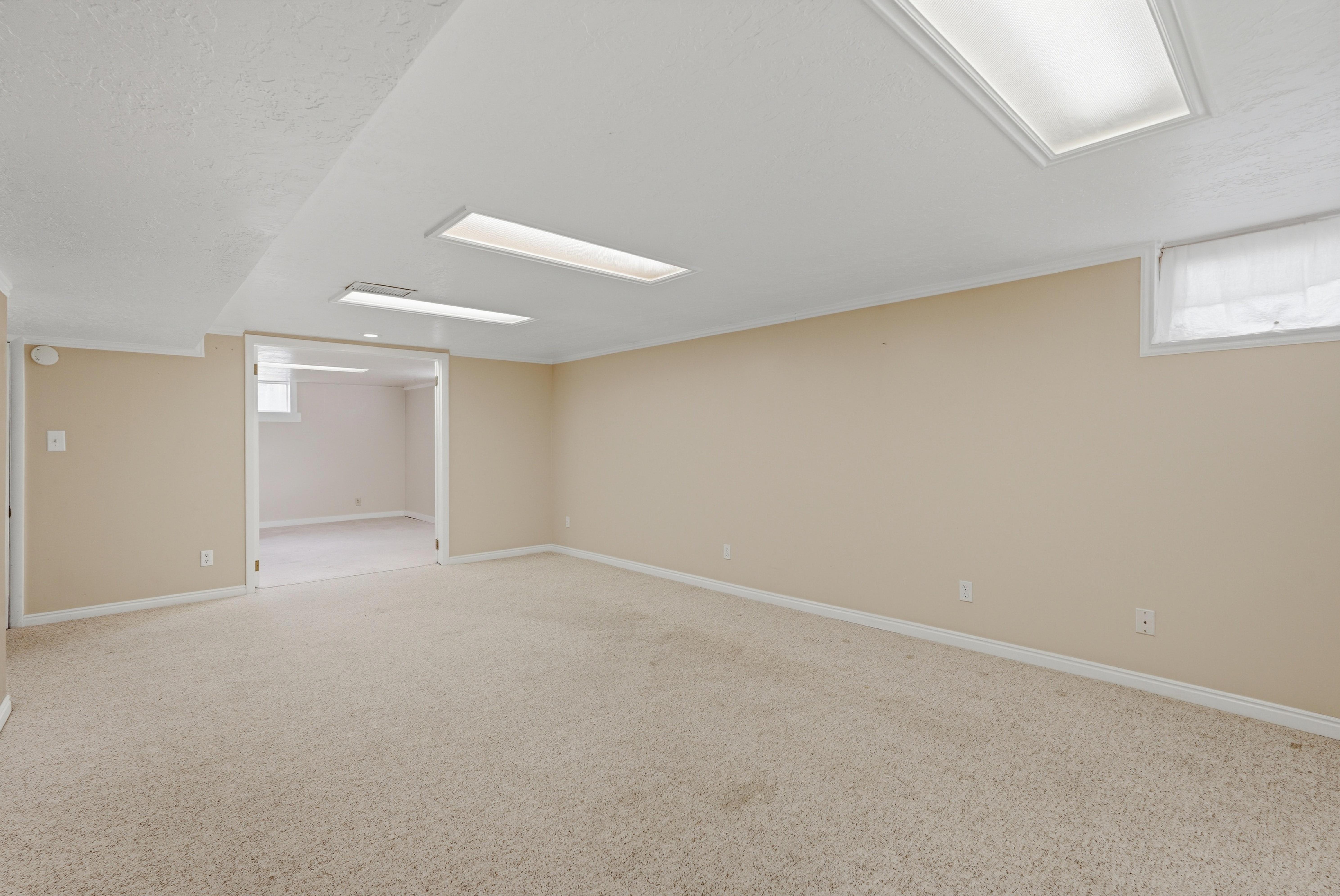Expansive carpeted room with neutral wall tones and white trim