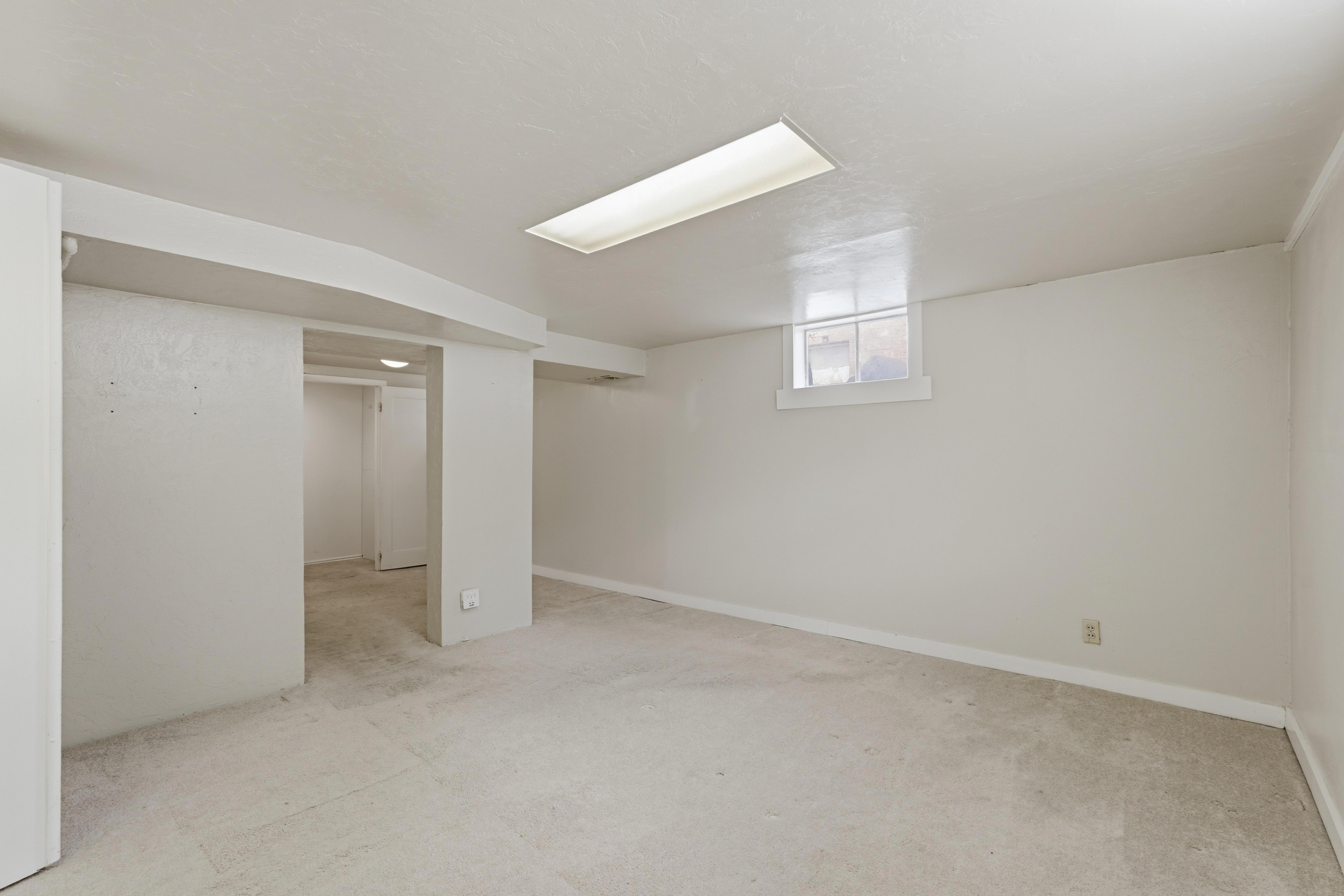 Spacious room featuring light-toned carpeting, a horizontal window, and recessed rectangular lighting