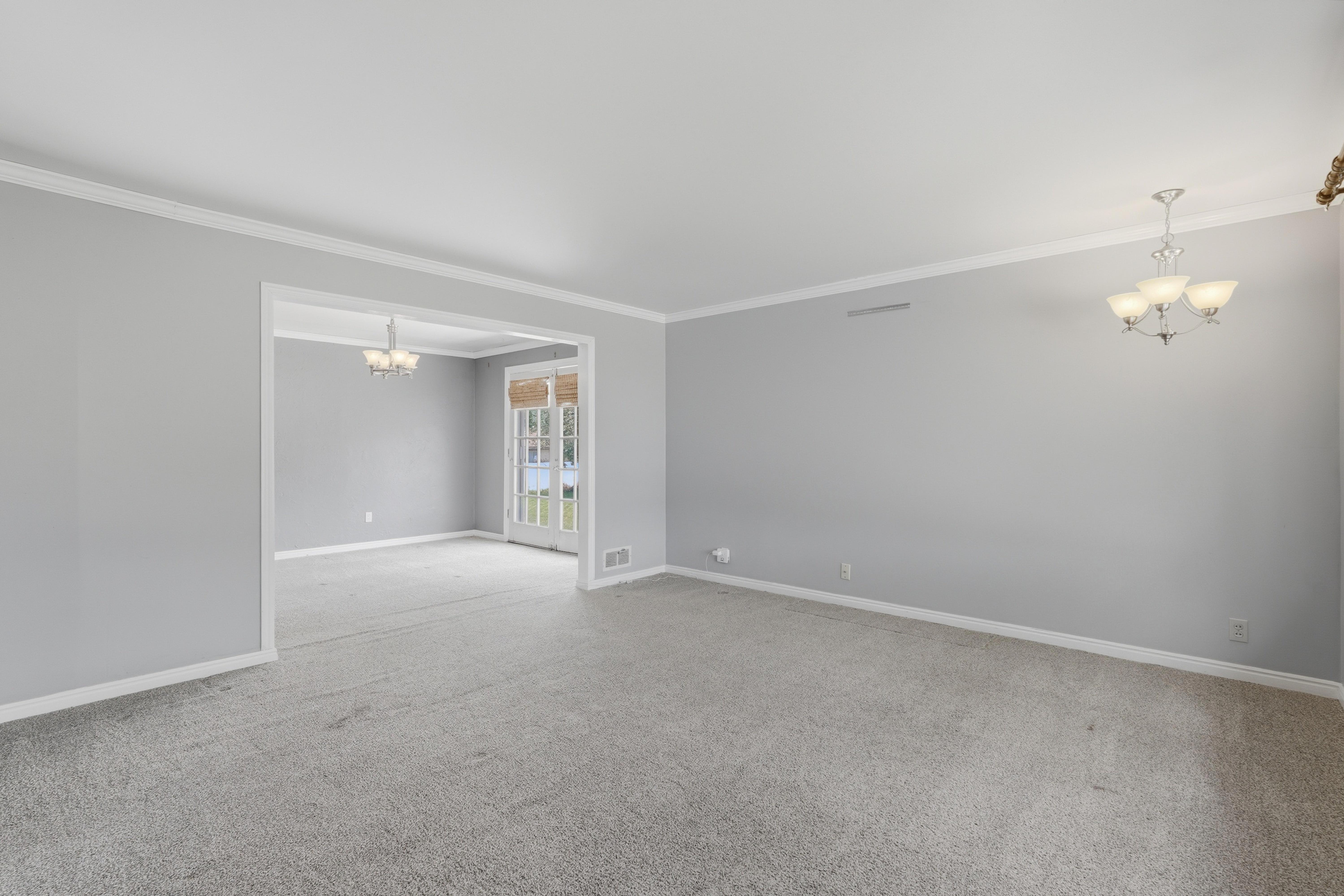 Spacious interior featuring light gray walls, white crown molding, and plush gray carpeting