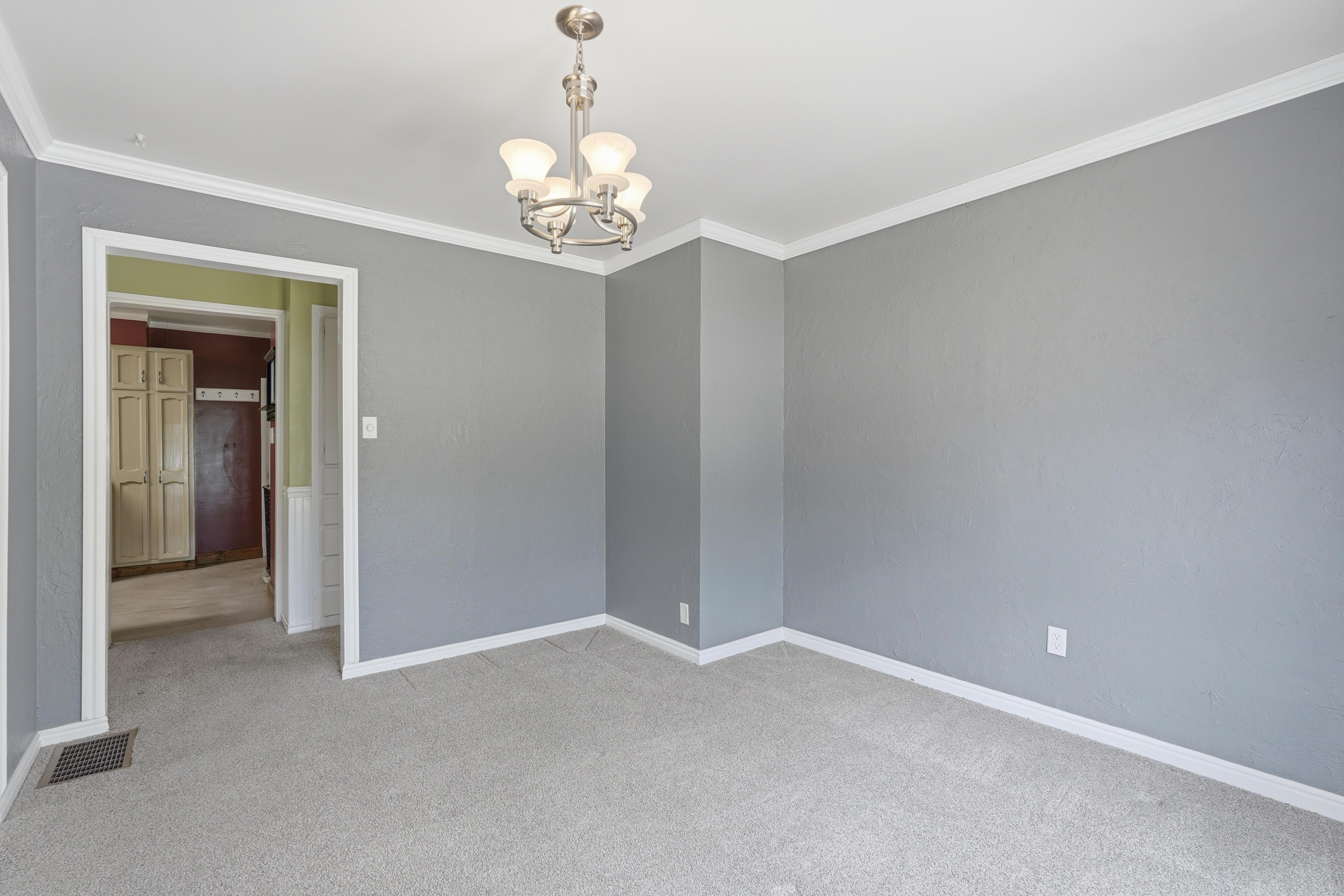 Light gray walls complement white crown molding and baseboards in this room featuring a brushed nickel chandelier