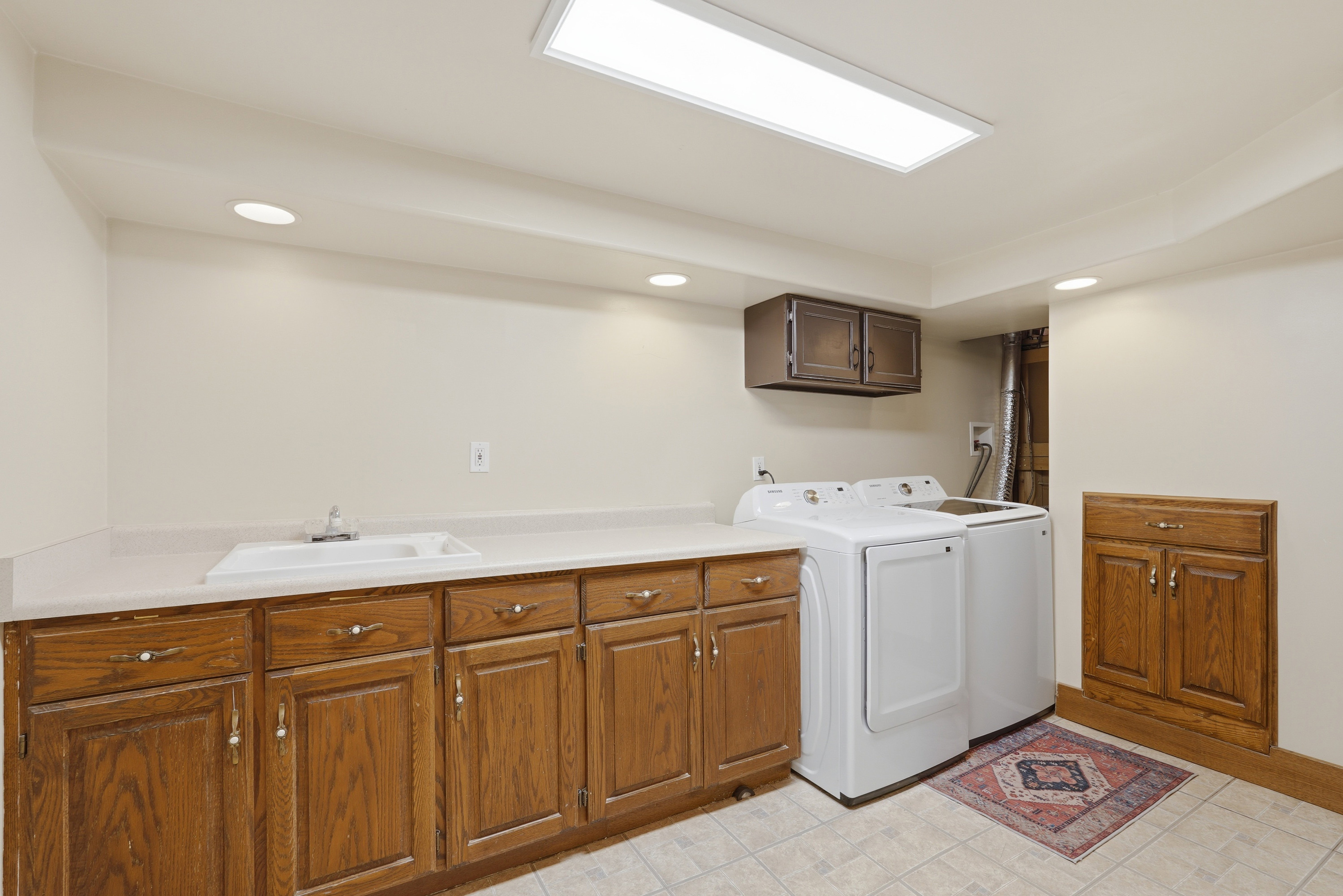 Utility area featuring extensive wood cabinetry, a utility sink, and ample countertop space