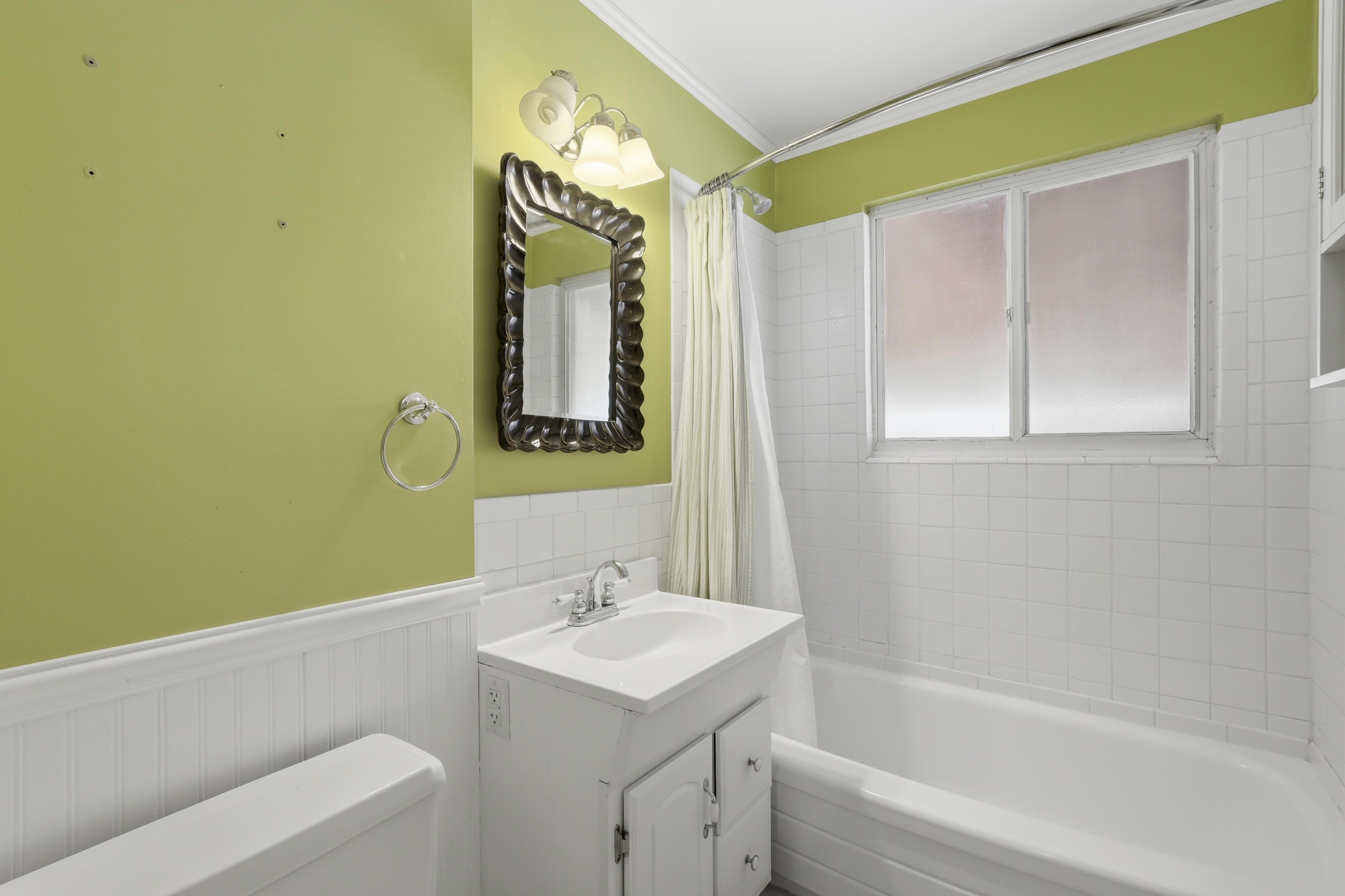 Bathroom featuring a white vanity with integrated sink, chrome faucet, and a wall-mounted mirror with an ornate frame