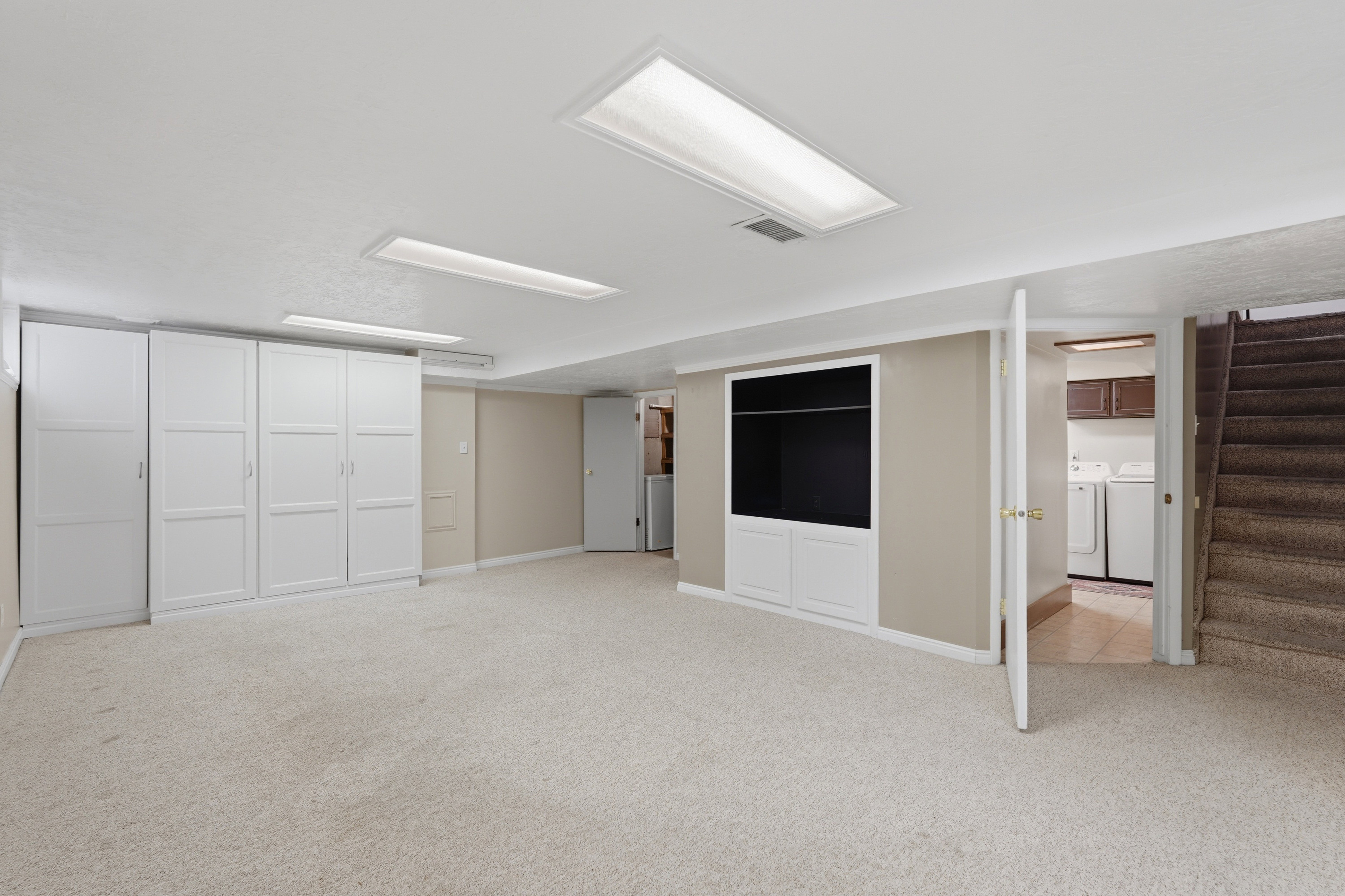 Spacious room featuring light-toned carpeting, ample built-in cabinetry, and recessed ceiling lighting