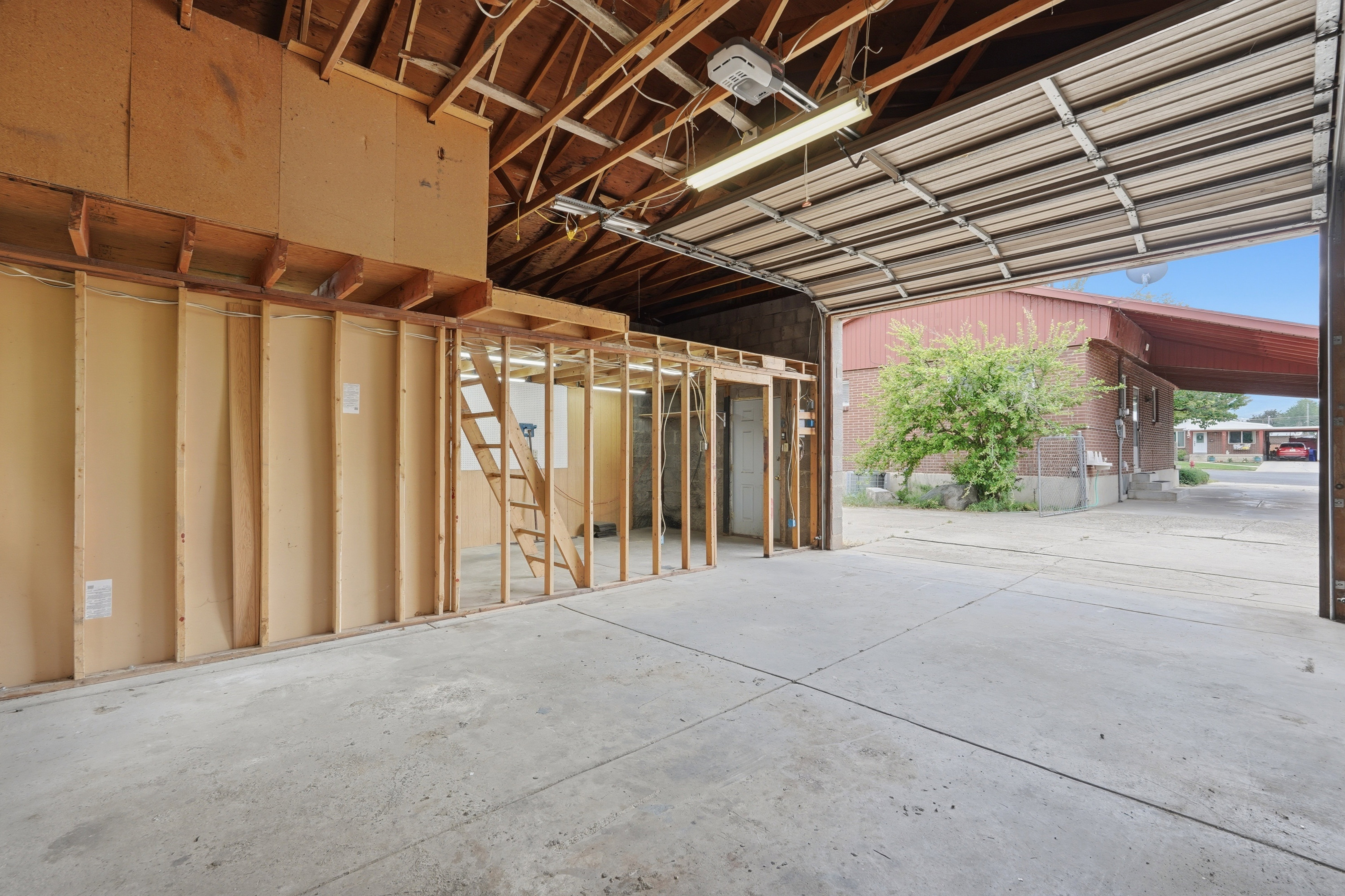 Spacious garage with exposed wood rafters, concrete flooring, and an overhead door
