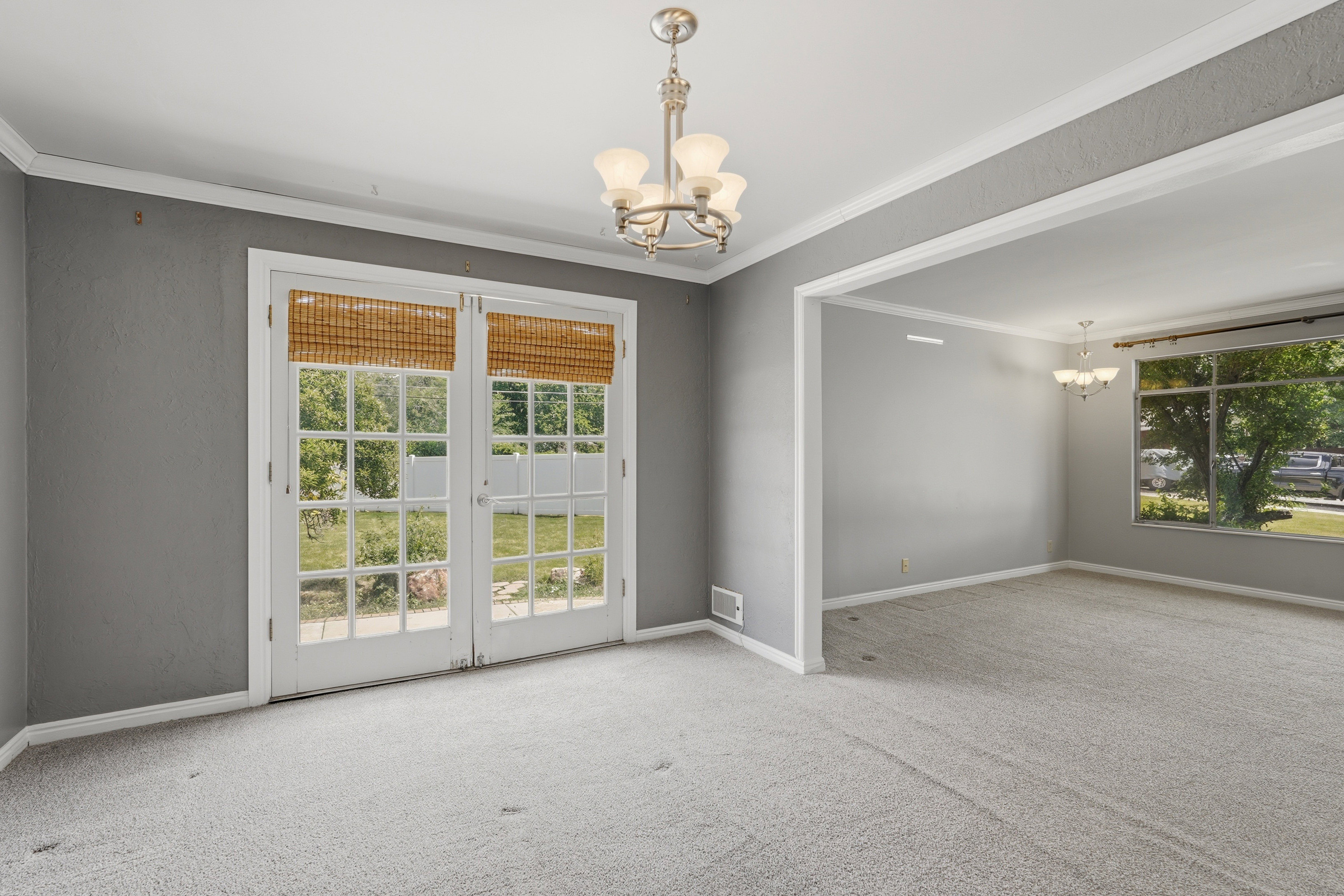 Spacious room featuring light gray carpeting and a double French door leading to an outdoor area