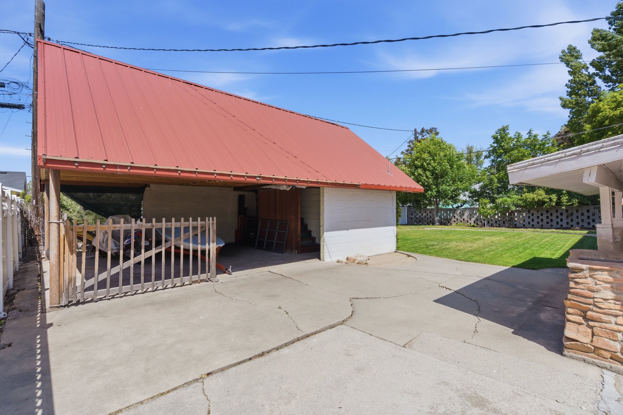 Detached structure featuring a red metal roof and a covered open-air storage area