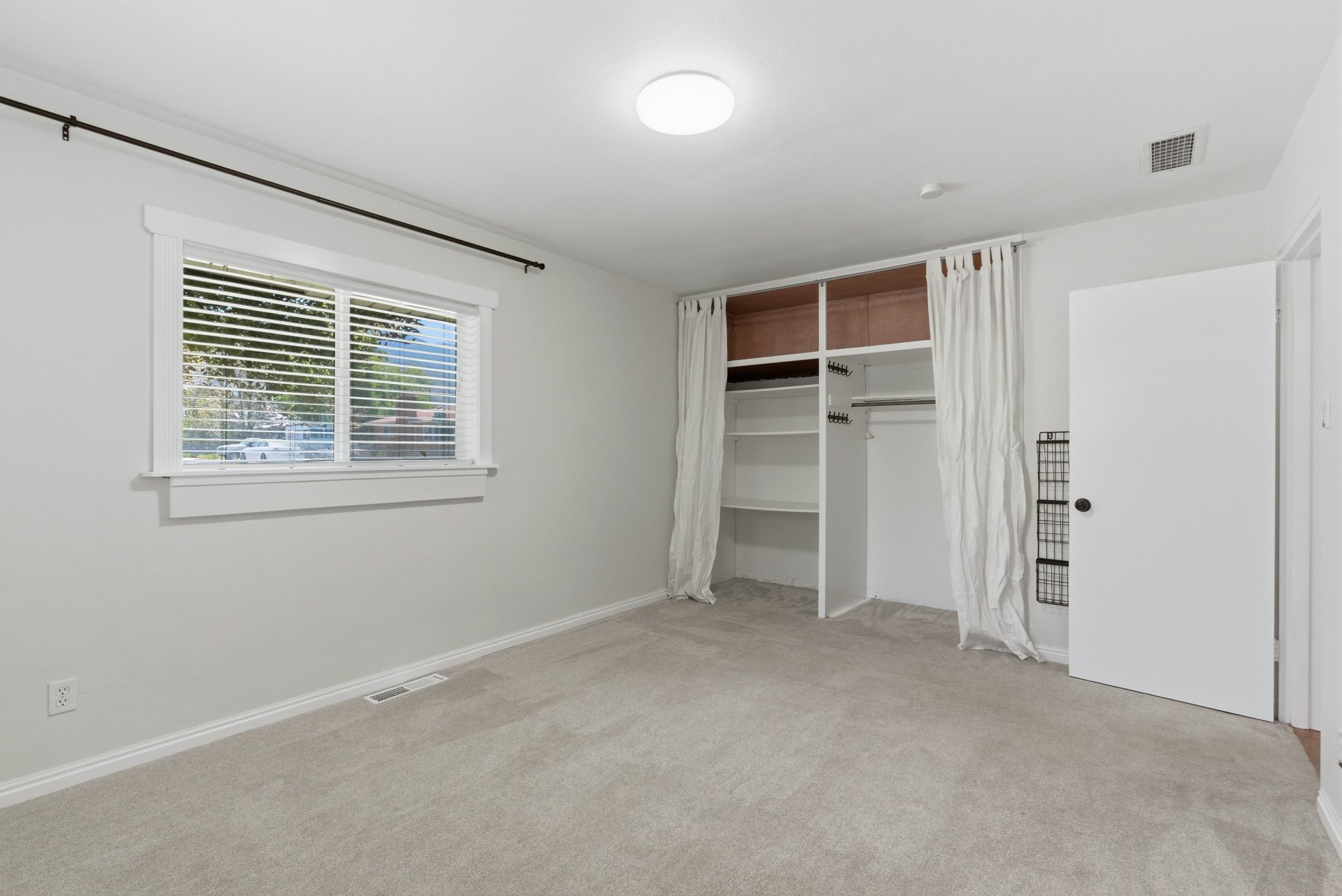Carpeted room with a built-in closet system featuring shelving and hanging space
