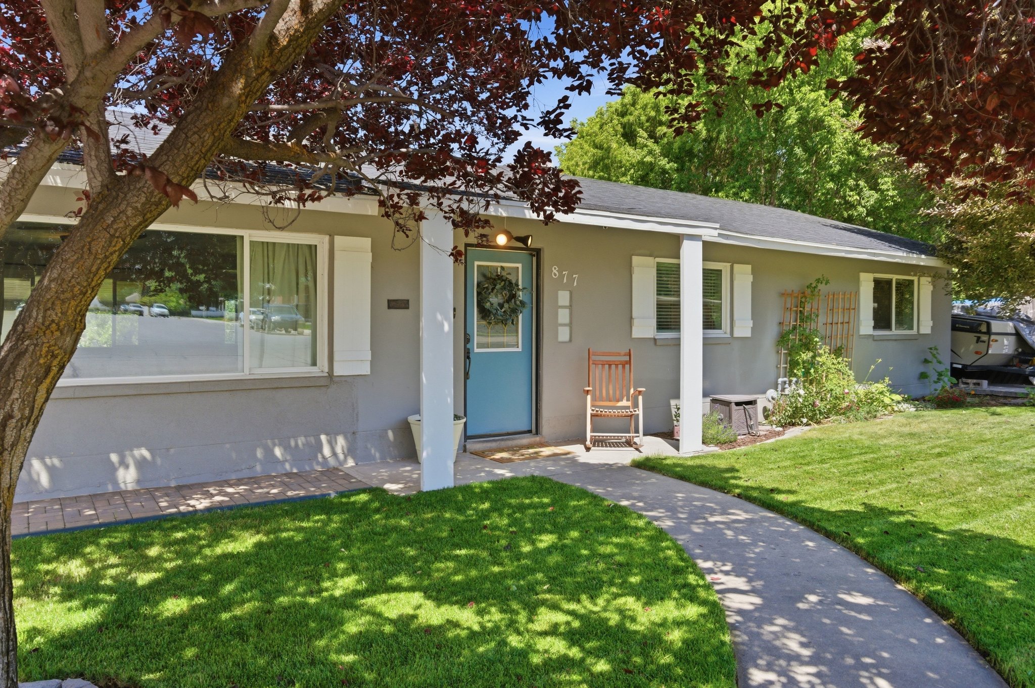 Single-story residence featuring a light gray exterior, white window trim, and a prominent blue entry door