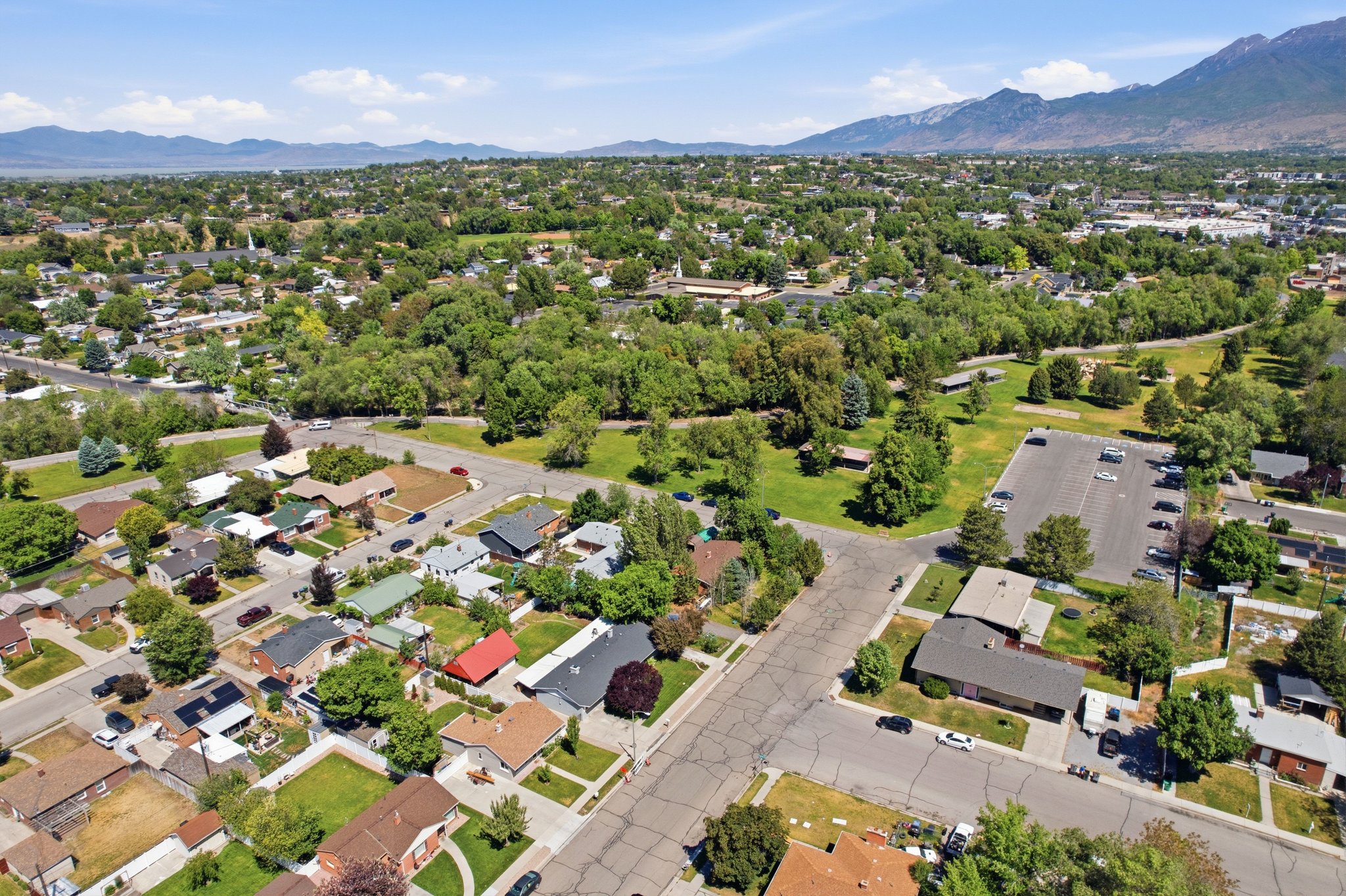 Expansive aerial view showcasing residential properties, tree-lined streets, and distant mountains