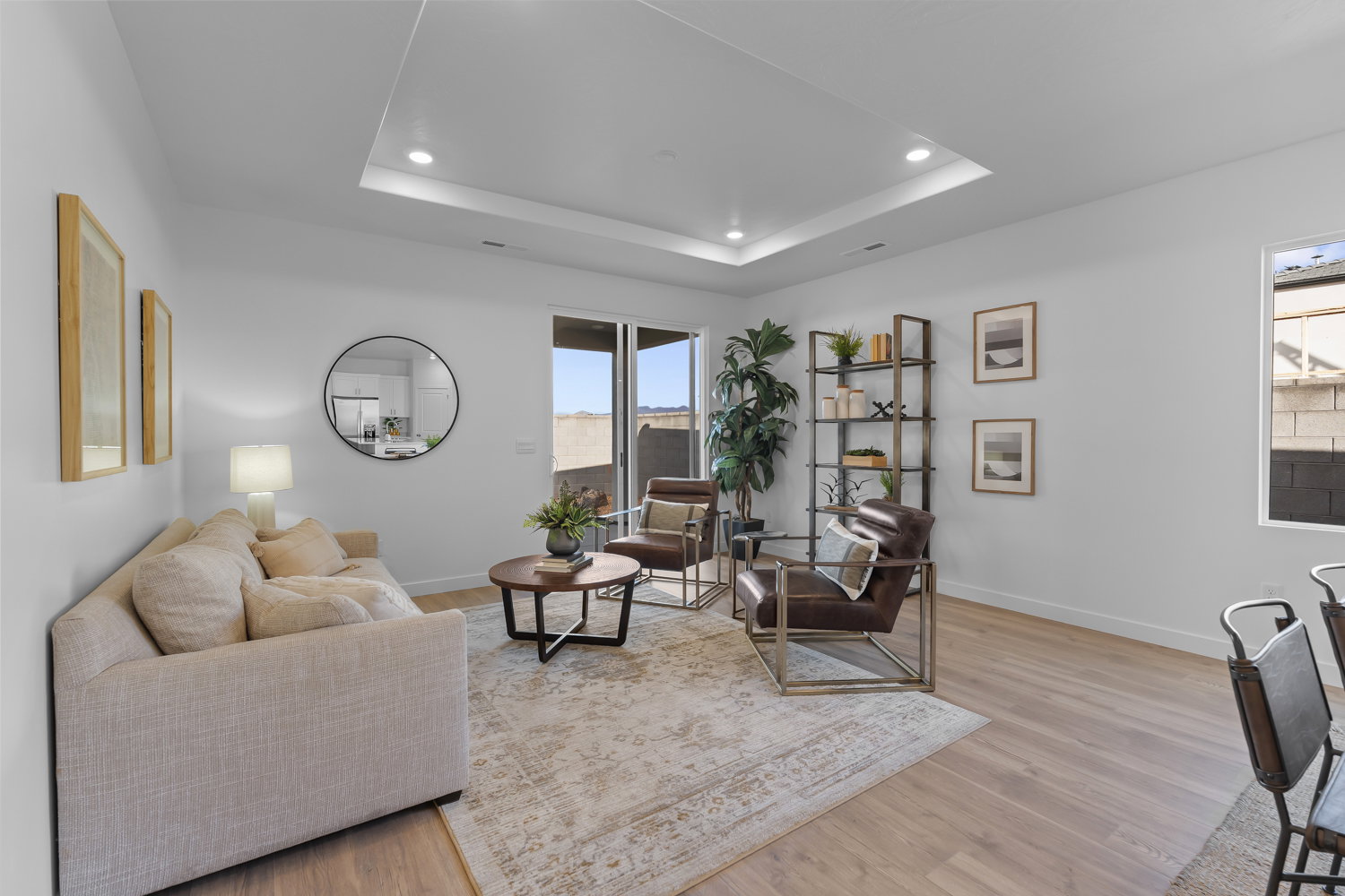 Light-filled living space featuring wood-finish flooring, a tray ceiling with recessed lighting, and a sliding glass door for outdoor access
