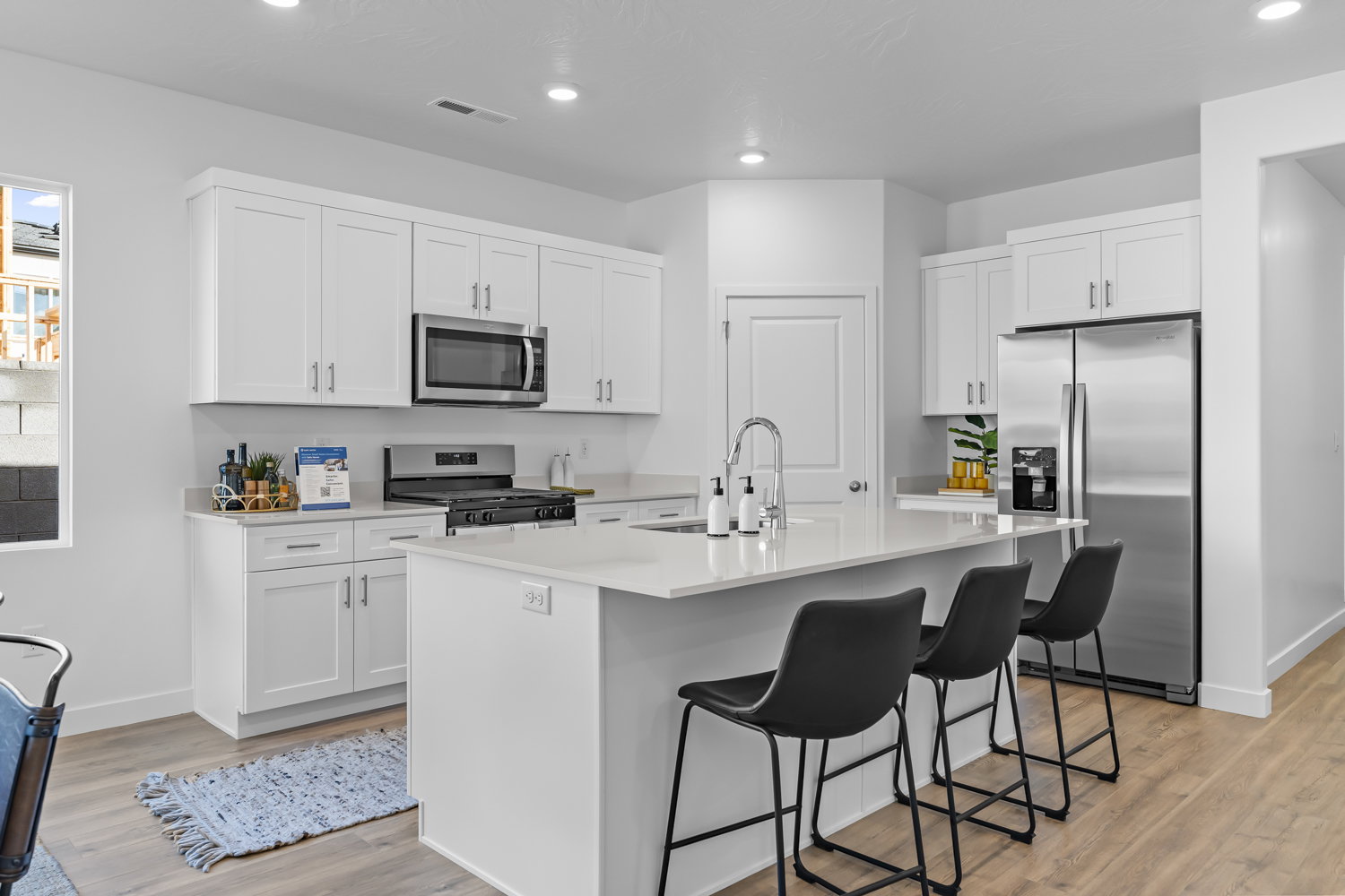 Modern kitchen featuring white shaker cabinetry, stainless steel appliances, a center island with countertop seating, recessed lighting, and wood-finish flooring