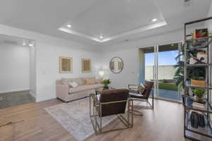 Living area featuring wood-finish flooring and a tray ceiling with recessed lighting