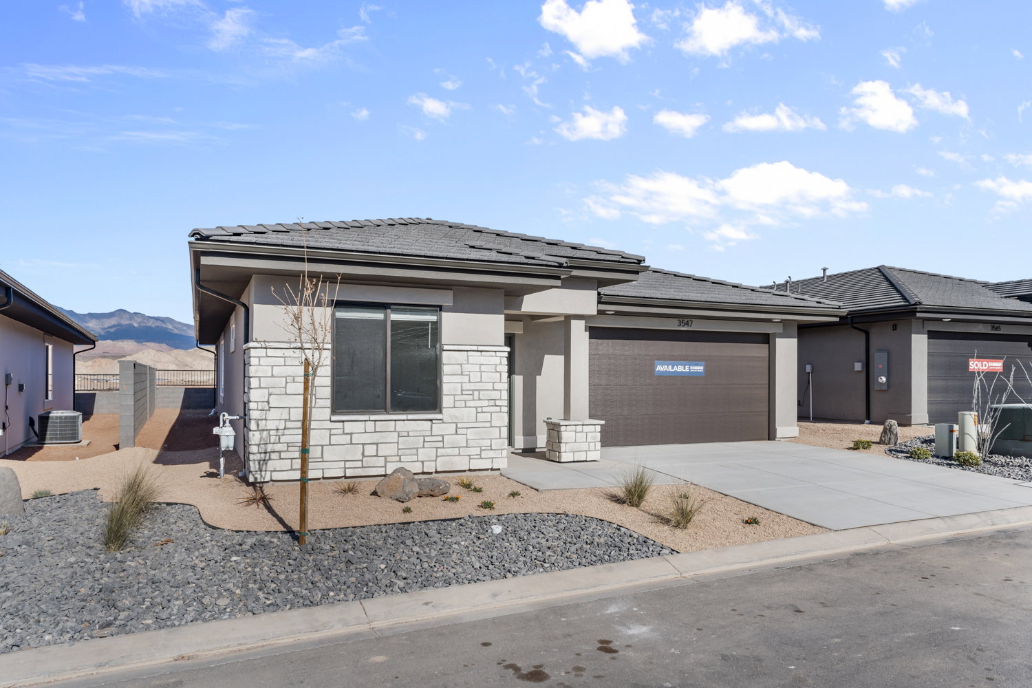 Contemporary single-story residence featuring a stone and stucco facade, a dark shingle roof, and an attached two-car garage