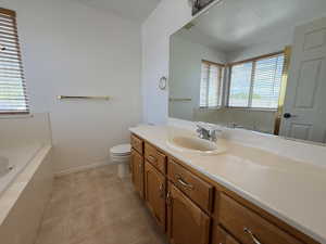Bathroom featuring a built-in tub, wood-finish vanity with an integrated sink, and a large wall-mounted mirror