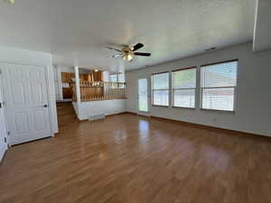 Spacious main living area featuring wood-finish flooring, a ceiling fan, and multiple windows with blinds