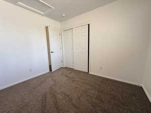 Carpeted room featuring white walls, a white paneled door, and a white bi-fold closet