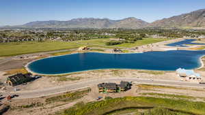 Expansive residential development featuring a large blue water body, multiple construction sites for residential structures, and paved roadways