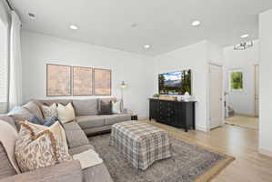 Living area featuring wood-finish flooring, recessed lighting, and a window with blinds