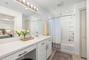 Bathroom featuring a double vanity with stone countertops, integrated sink, brushed nickel fixtures, and white cabinetry with matte black hardware