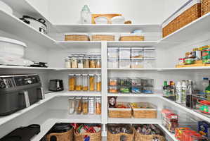 Custom pantry featuring white shelving, ample storage solutions, and built-in corner shelving