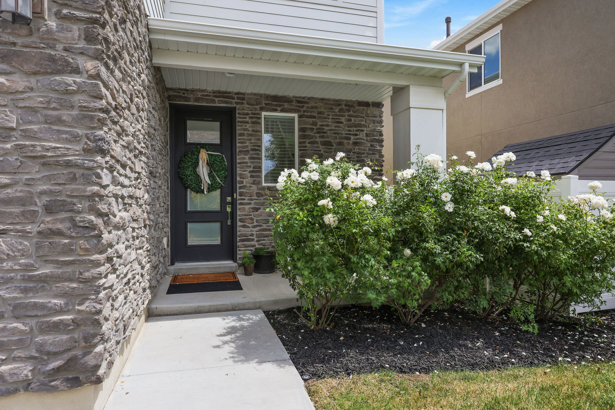 Front entrance featuring a dark paneled door with three inset windows, framed by stacked stone siding