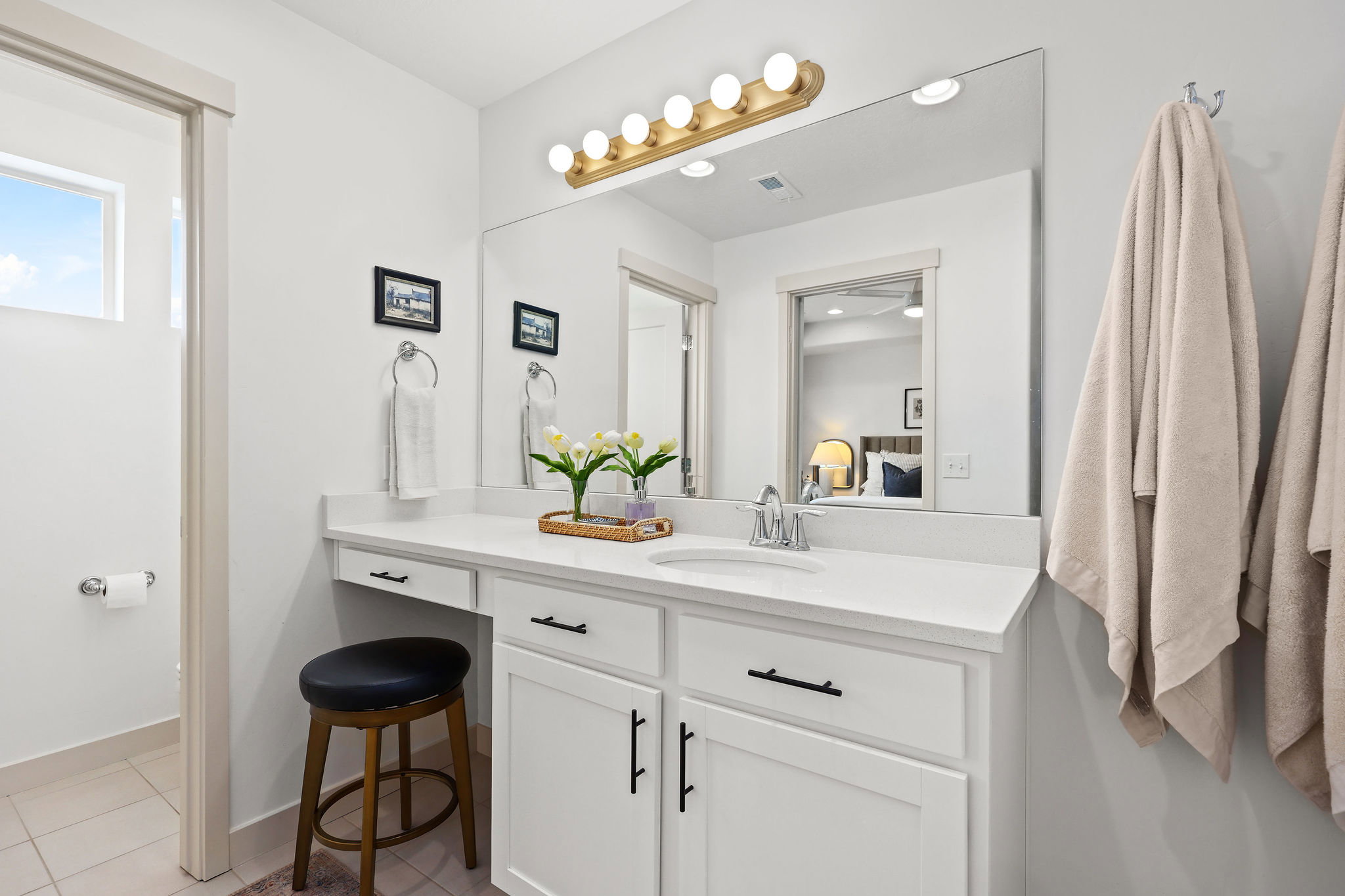 Bathroom vanity featuring a single basin sink, white cabinetry with black hardware, and a light-colored countertop