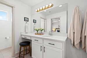 Bathroom vanity featuring a single basin sink, white cabinetry with black hardware, and a light-colored countertop