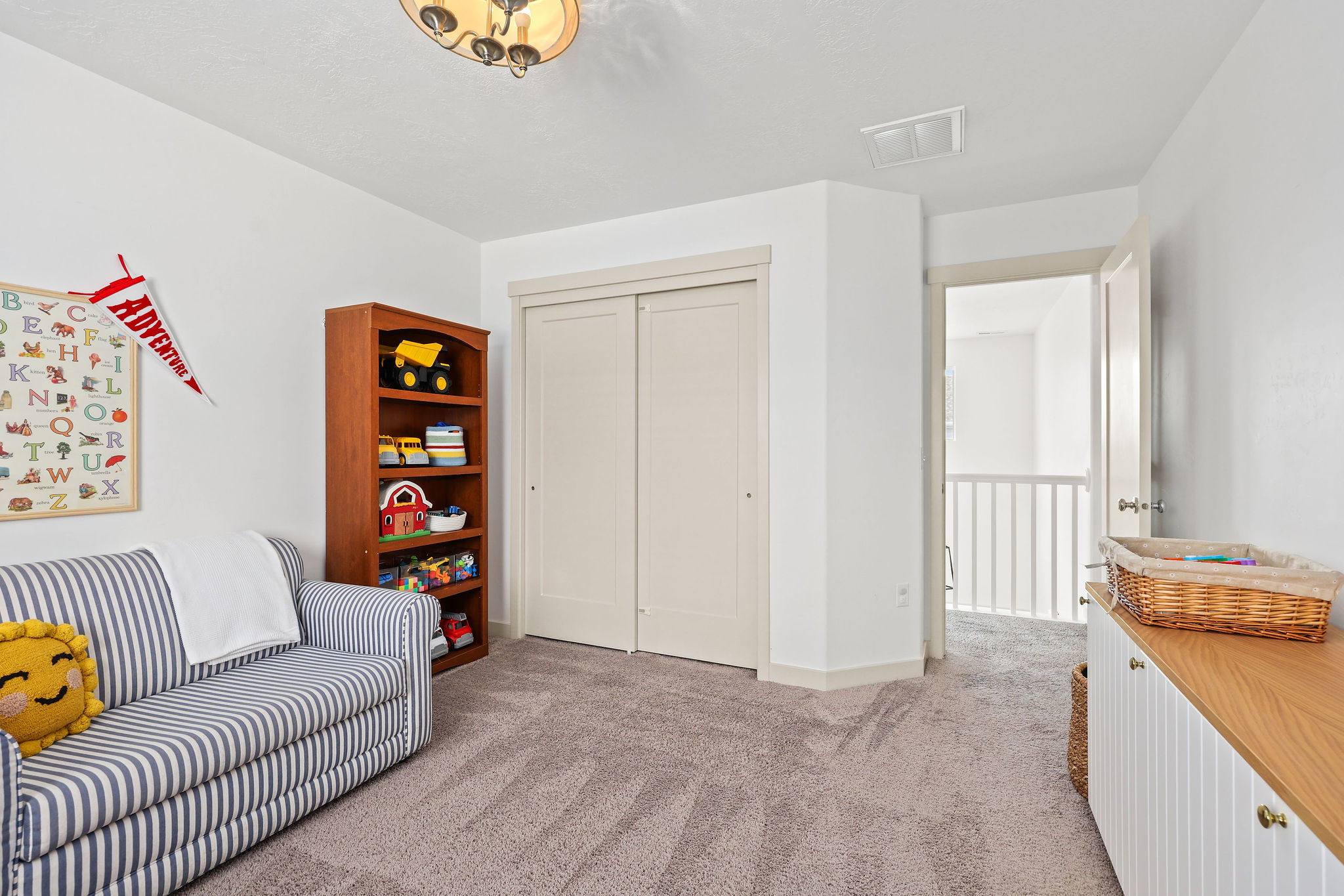 Carpeted room featuring a double-door closet, a built-in storage unit with a wood-finish top, and a ceiling-mounted light fixture