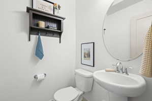 Pedestal sink with chrome fixtures and a circular frameless mirror