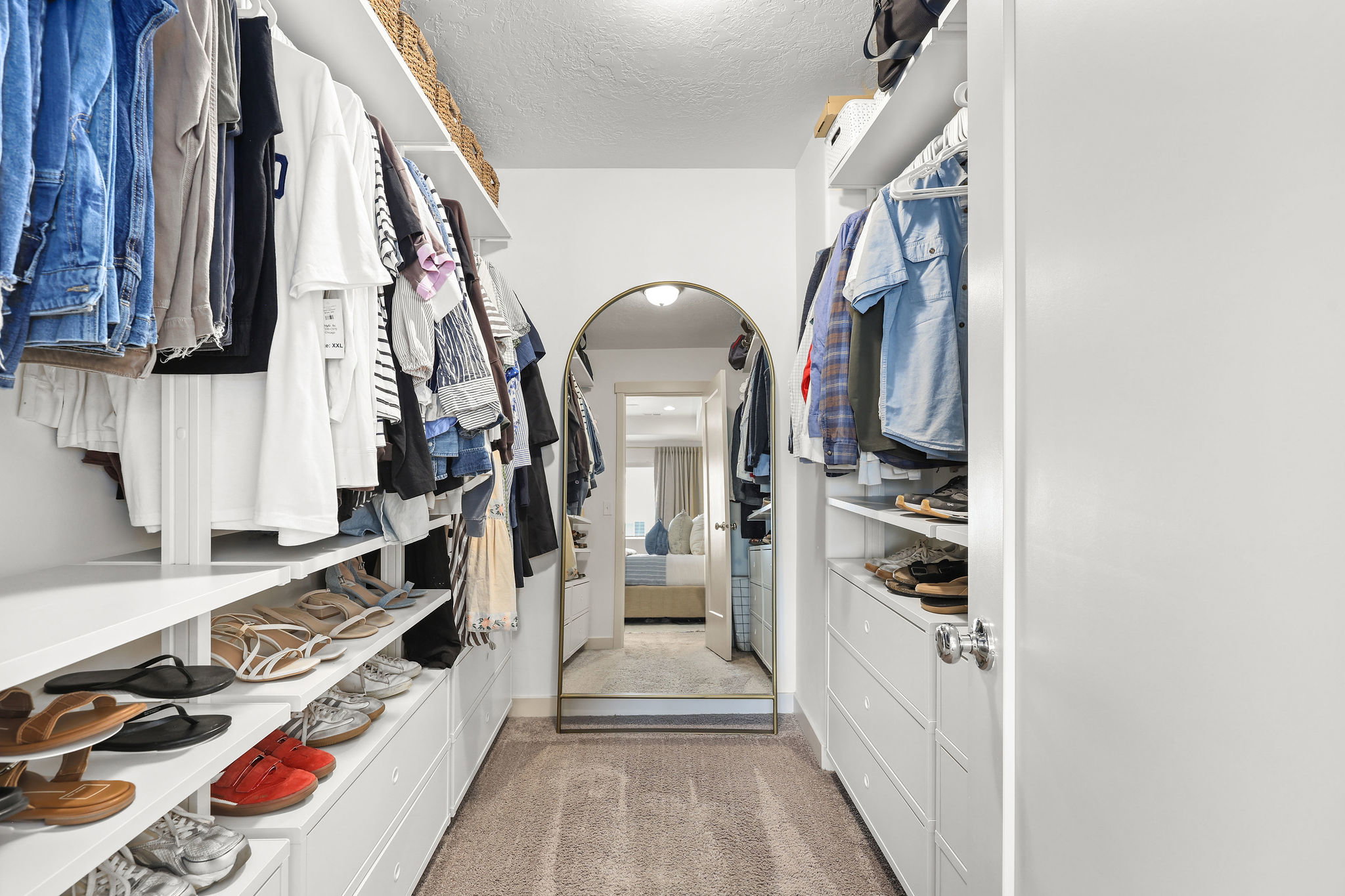 Walk-through closet featuring built-in shelving, hanging rods, integrated drawers, and carpet flooring