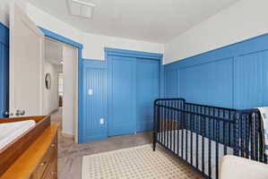 Carpeted room featuring beadboard wall paneling, a sliding closet door, and a white ceiling