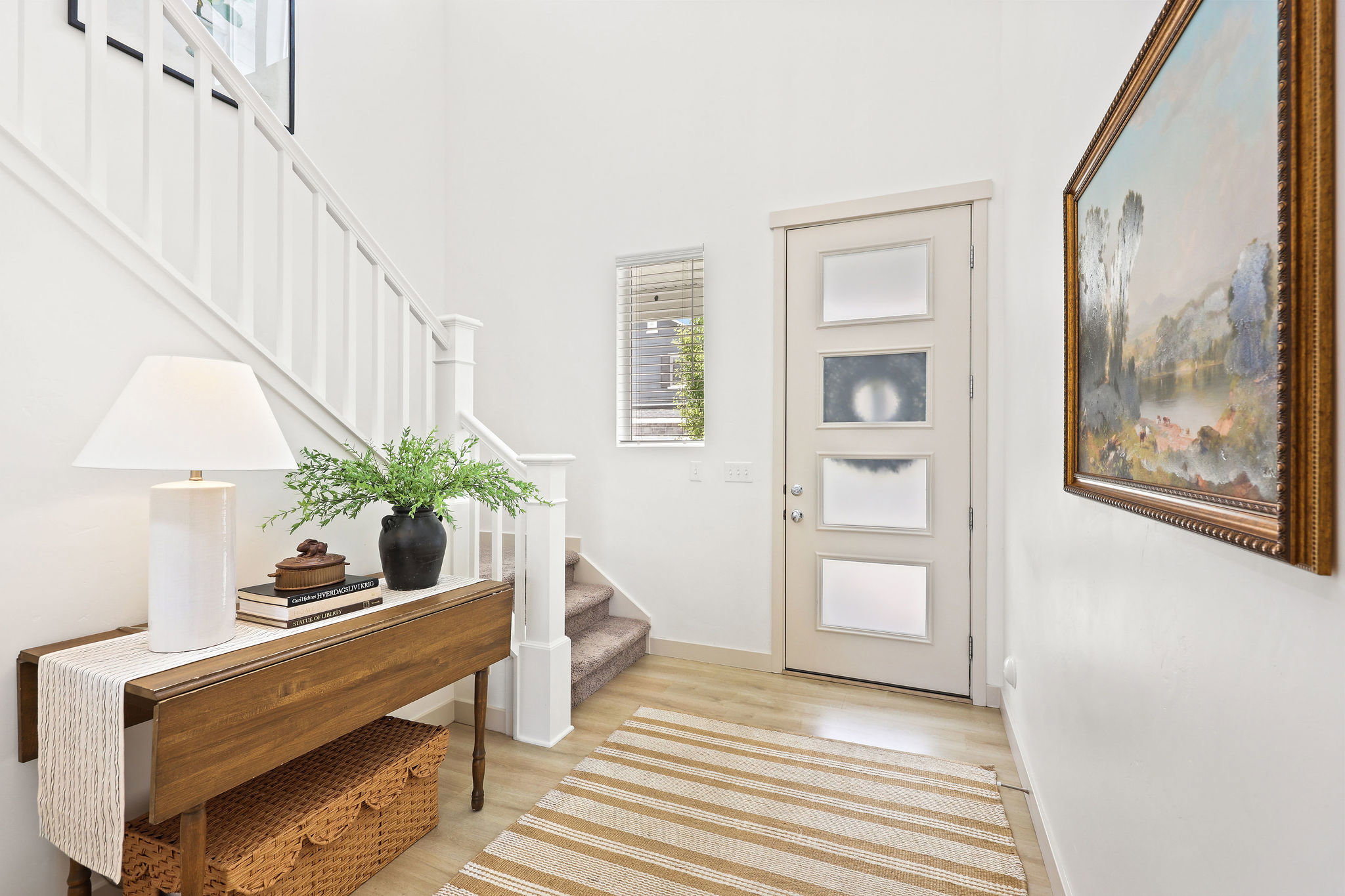 Entryway featuring light wood-finish flooring, a contemporary staircase with white balusters, and a modern door with frosted glass panels