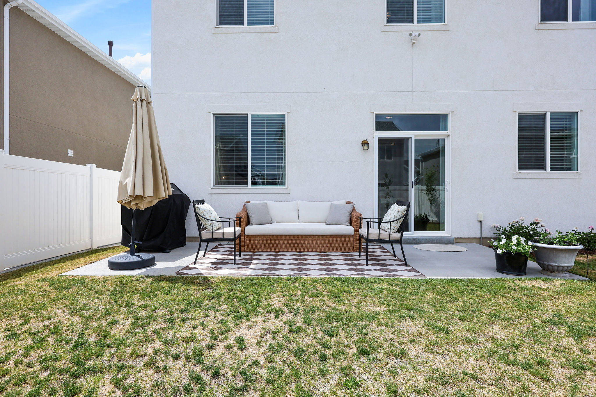 Rear exterior featuring a concrete patio, sliding glass door, and white vinyl fencing