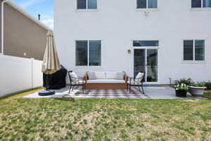 Rear exterior featuring a concrete patio, sliding glass door, and white vinyl fencing