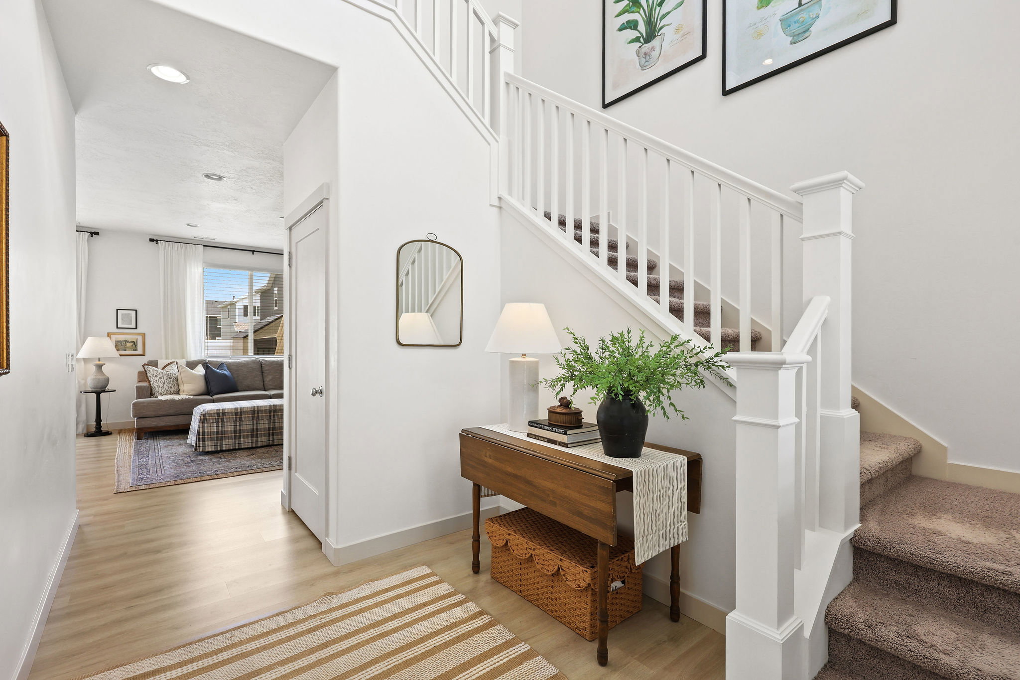 Entry foyer featuring light wood-finish flooring, white walls, and a staircase with white balusters and carpeted treads