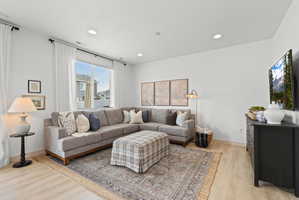 Bright living area featuring light wood-finish flooring and recessed lighting