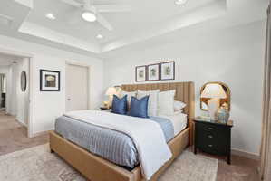 Spacious bedroom featuring a tray ceiling with recessed lighting and a ceiling fan, a neutral color palette, and carpeted flooring