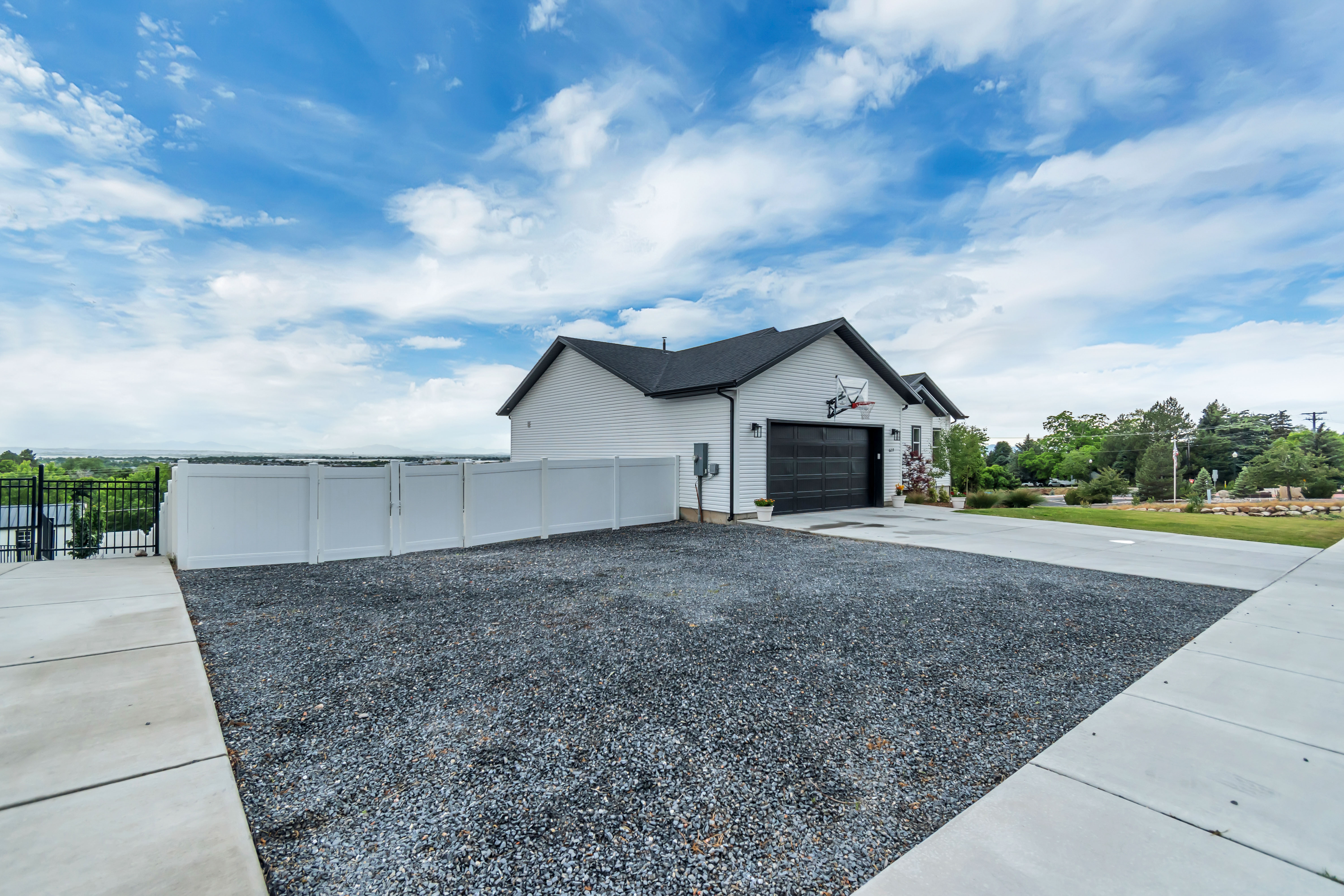 White sided exterior featuring a black garage door and dark roof