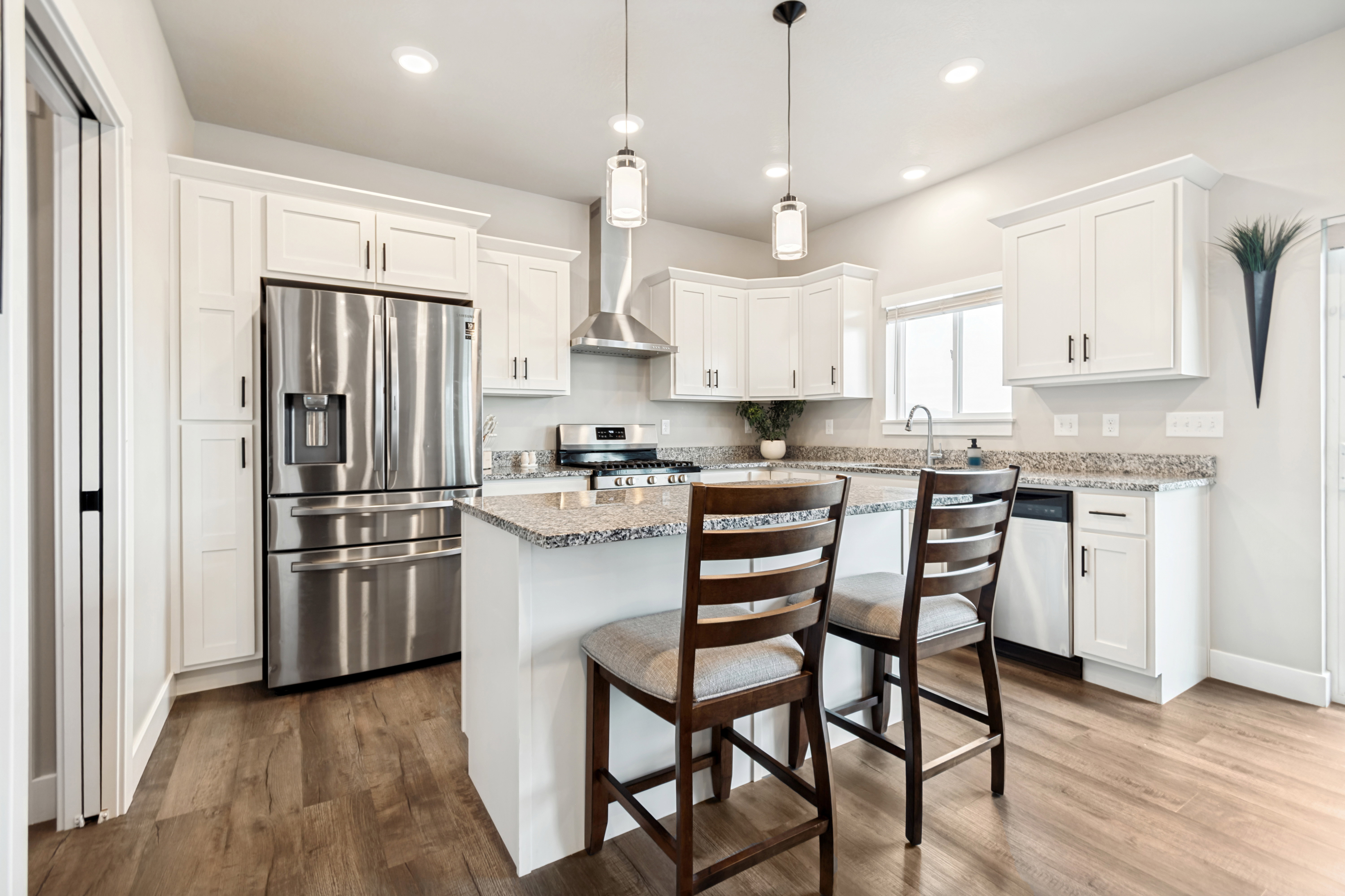 Modern kitchen featuring white cabinetry, granite countertops, and stainless steel appliances