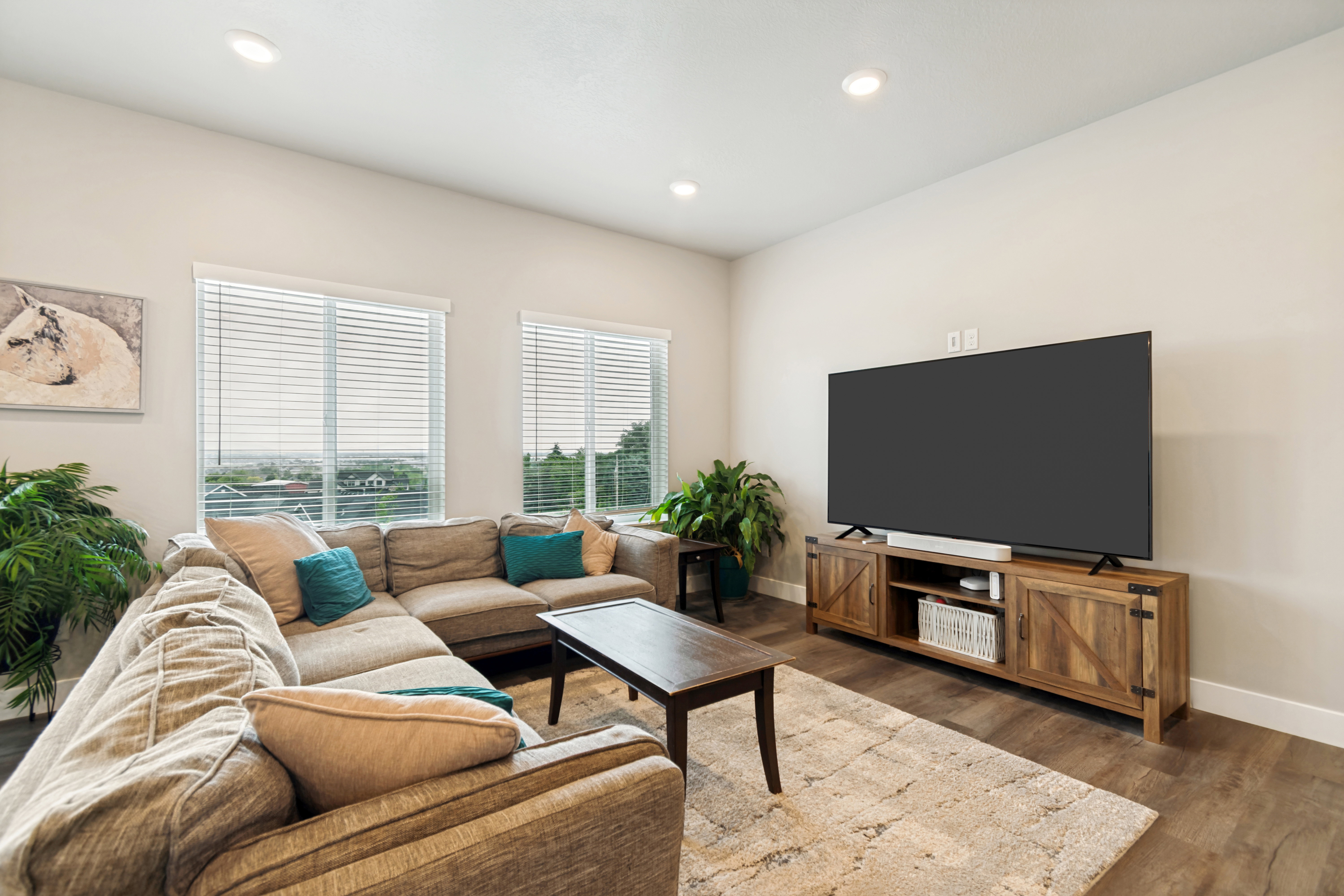 Living area featuring wood-finish flooring, recessed lighting, and large windows with horizontal blinds