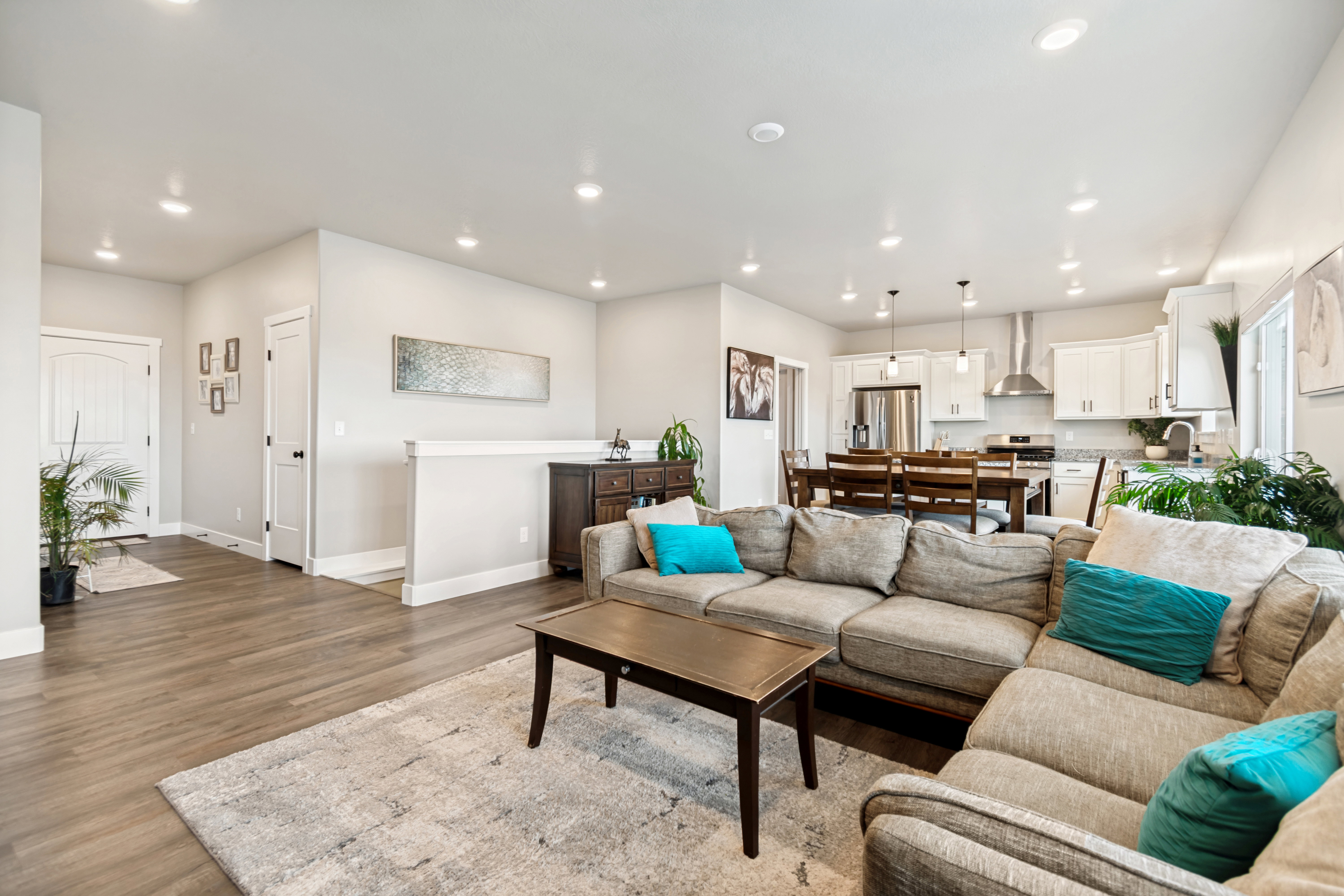 Open-concept living space featuring wood-finish flooring, recessed lighting, and a kitchen with white cabinetry and stainless steel appliances