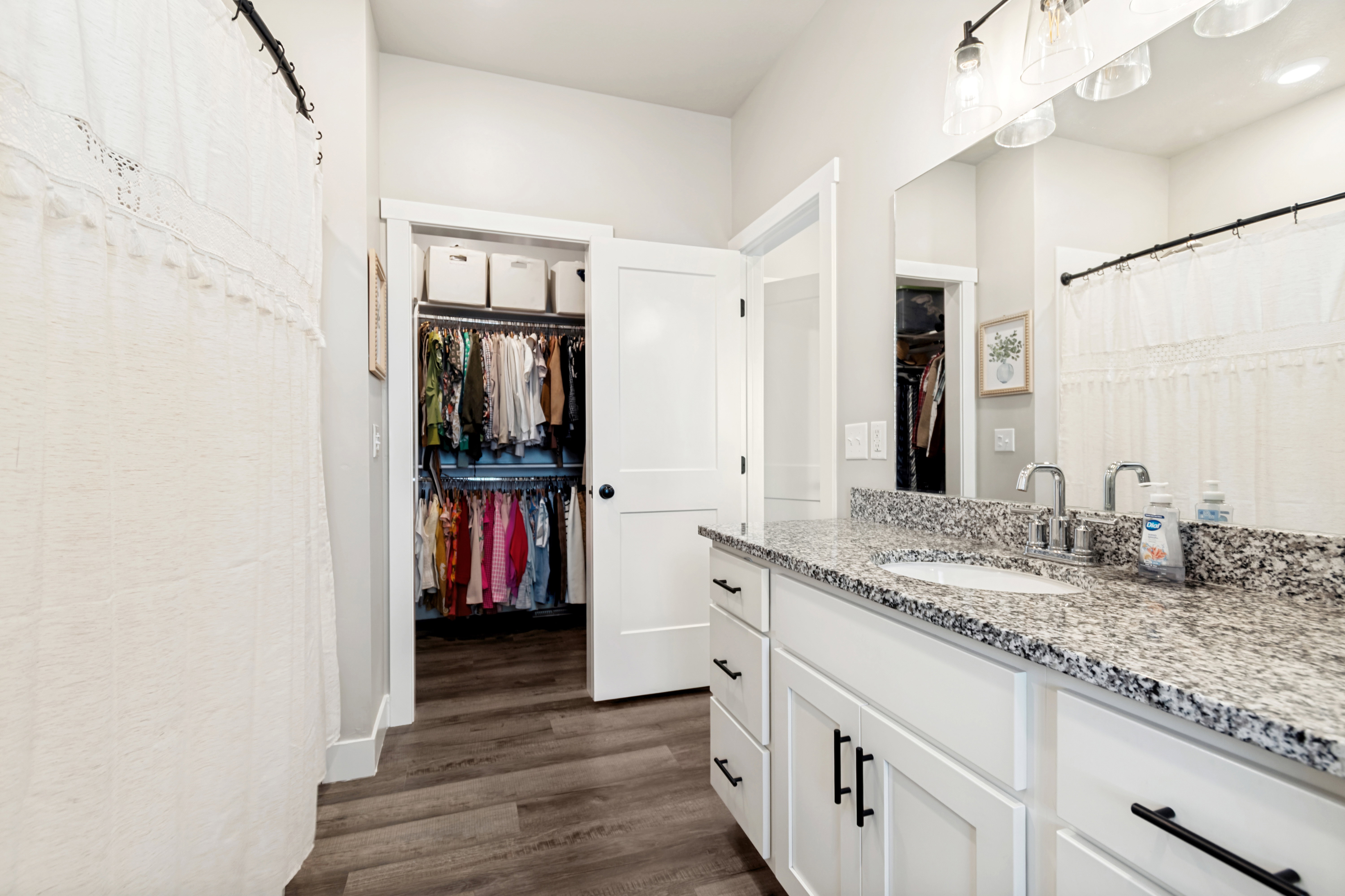 Bathroom vanity featuring a speckled countertop, dual under-mount sinks, and white shaker-style cabinetry with matte black hardware