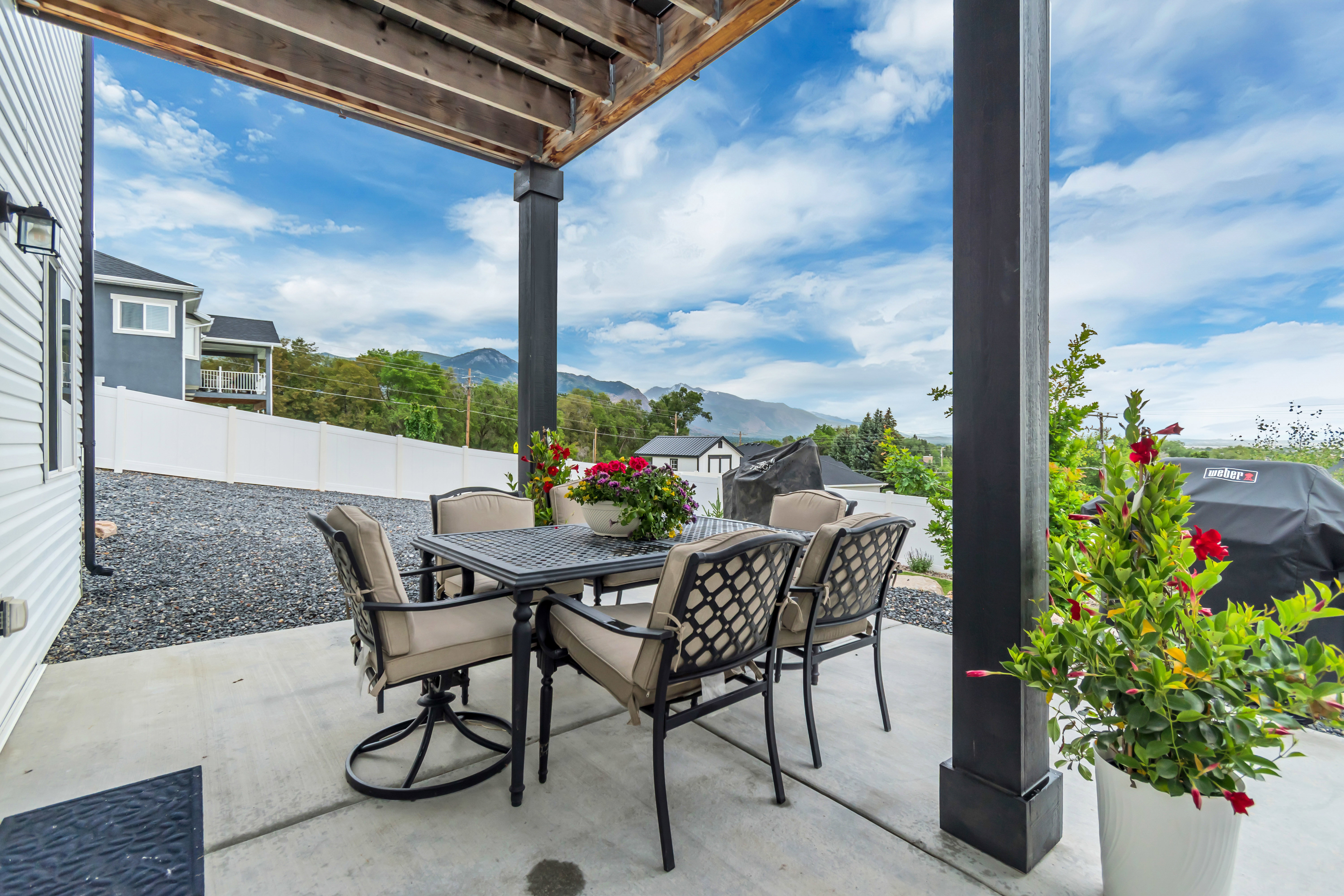 Covered patio with concrete flooring, supported by dark wood-finish posts