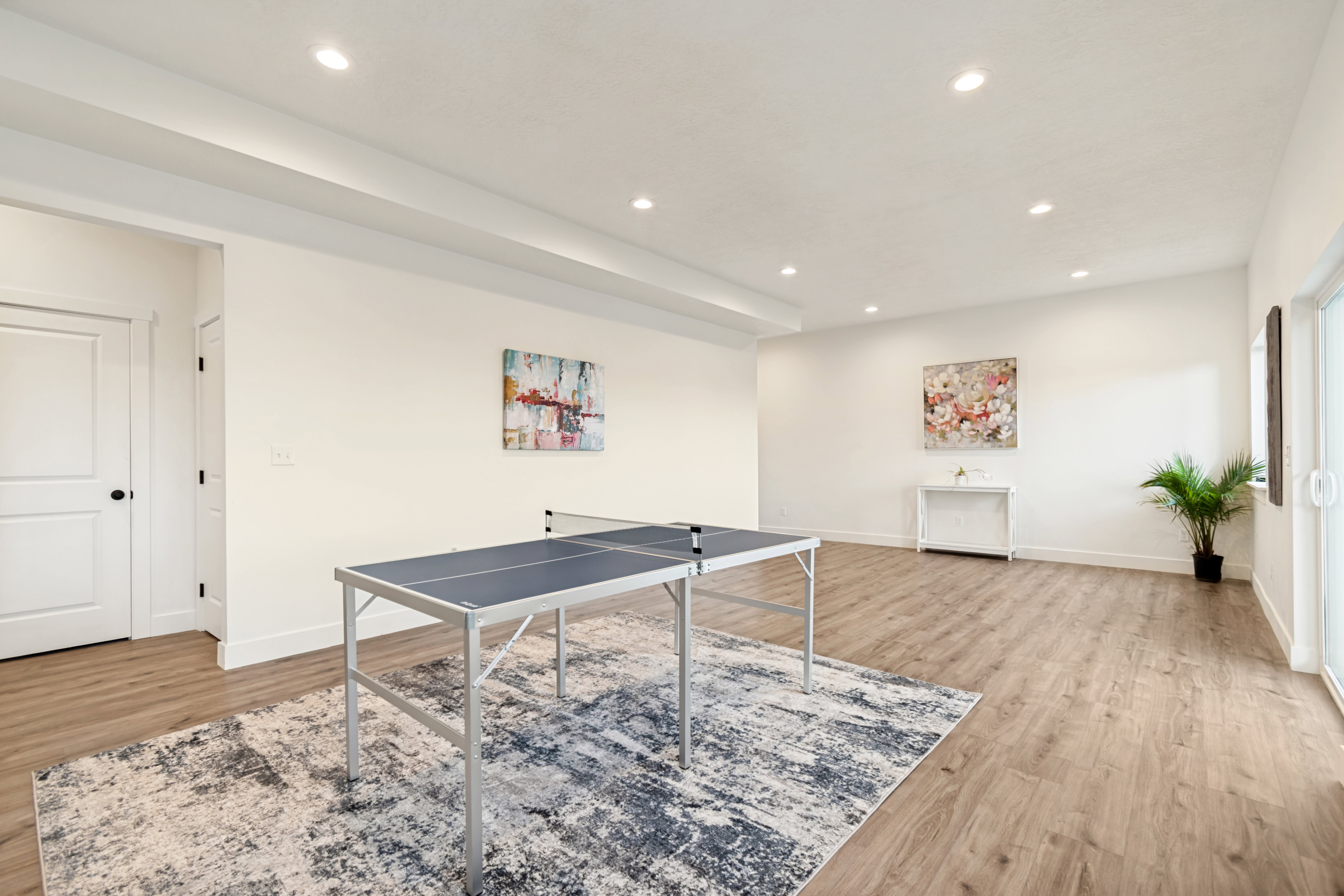 Spacious room featuring wood-finish flooring, white walls, and recessed lighting