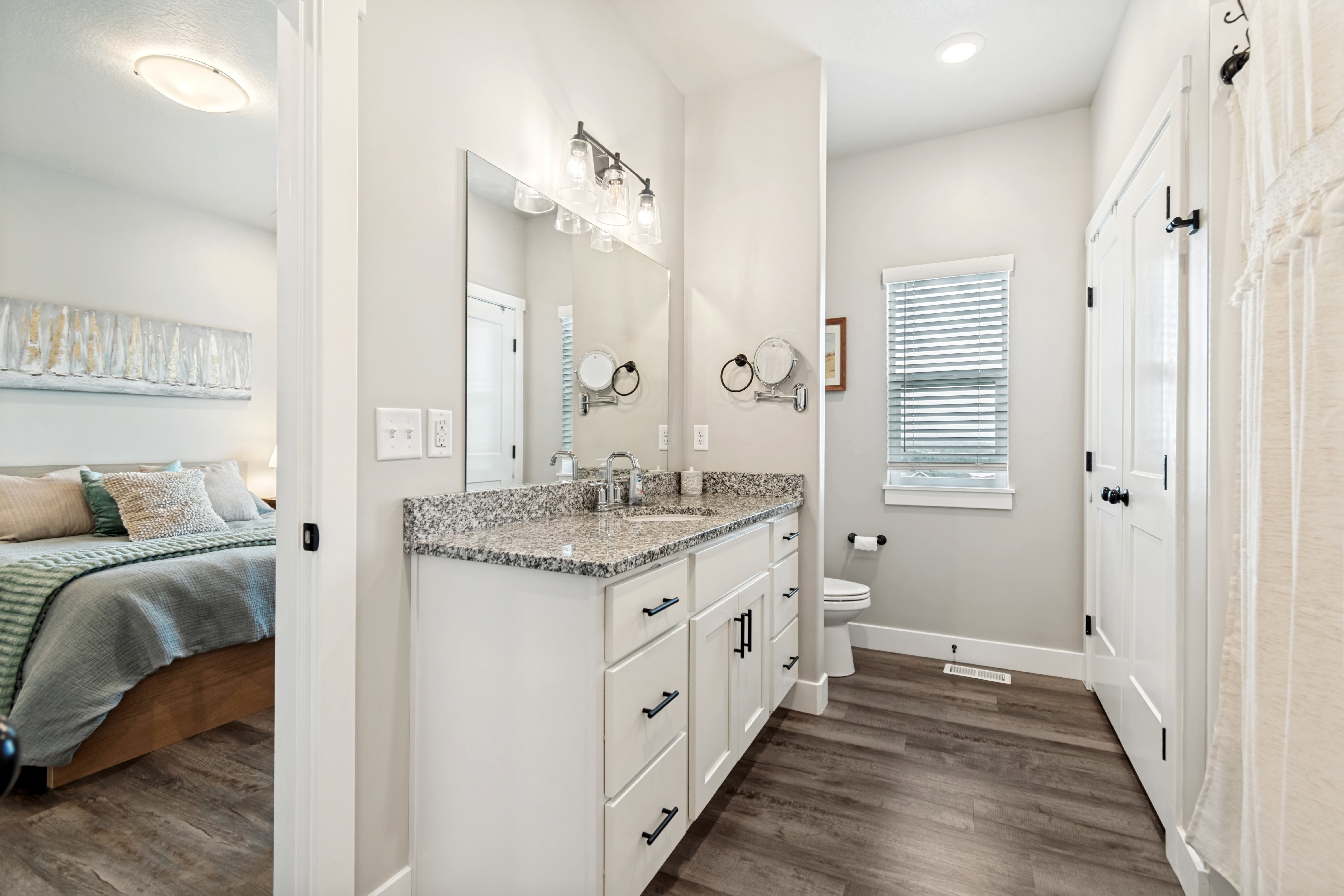 Bathroom featuring a white vanity with a granite-style countertop, dual sinks, and matte black hardware